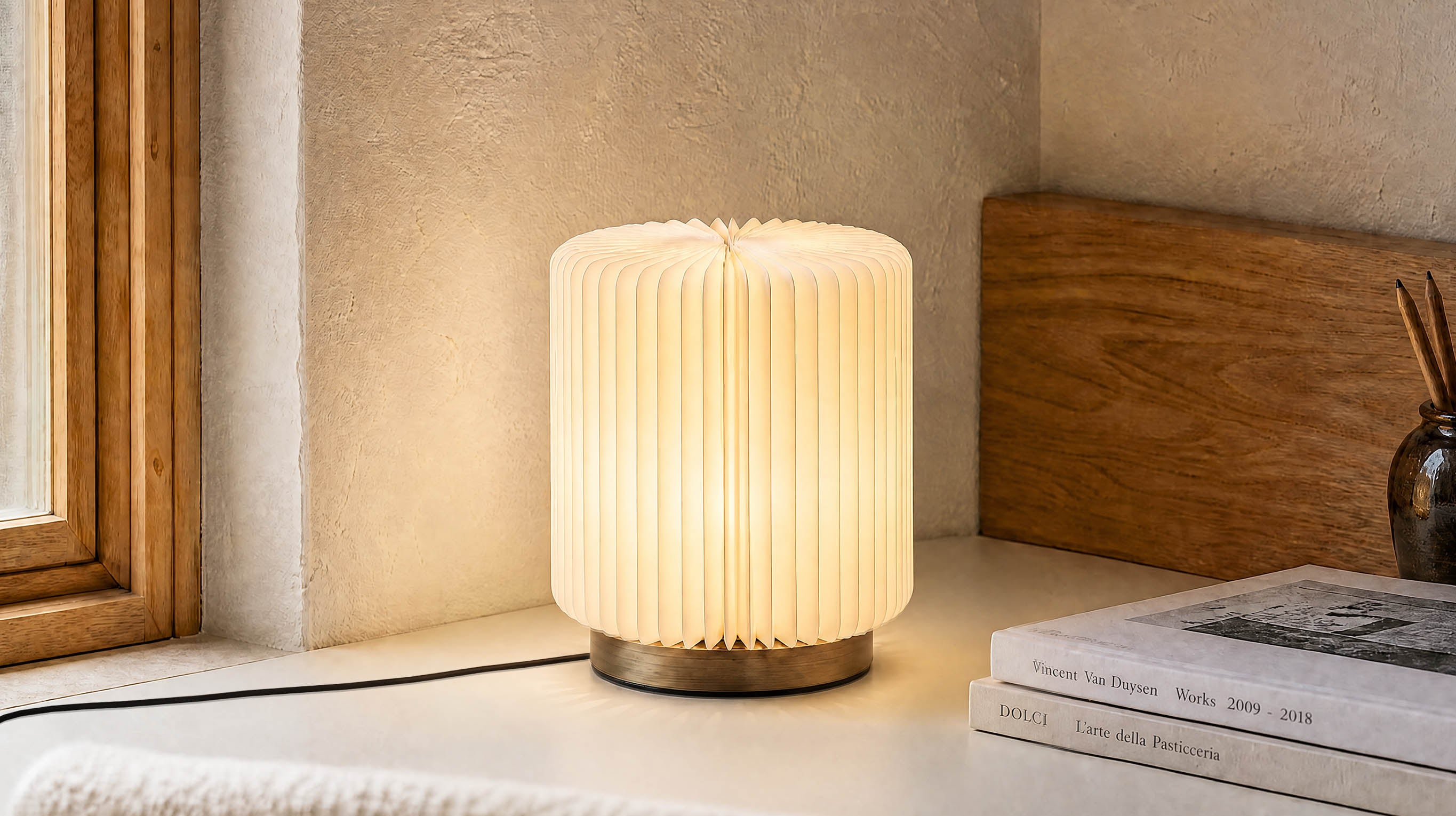 The artamore Bamboo Zen Desk Lamp casting a gentle, healing glow through its bamboo-inspired accordion paper shade in a serene minimalist setting.