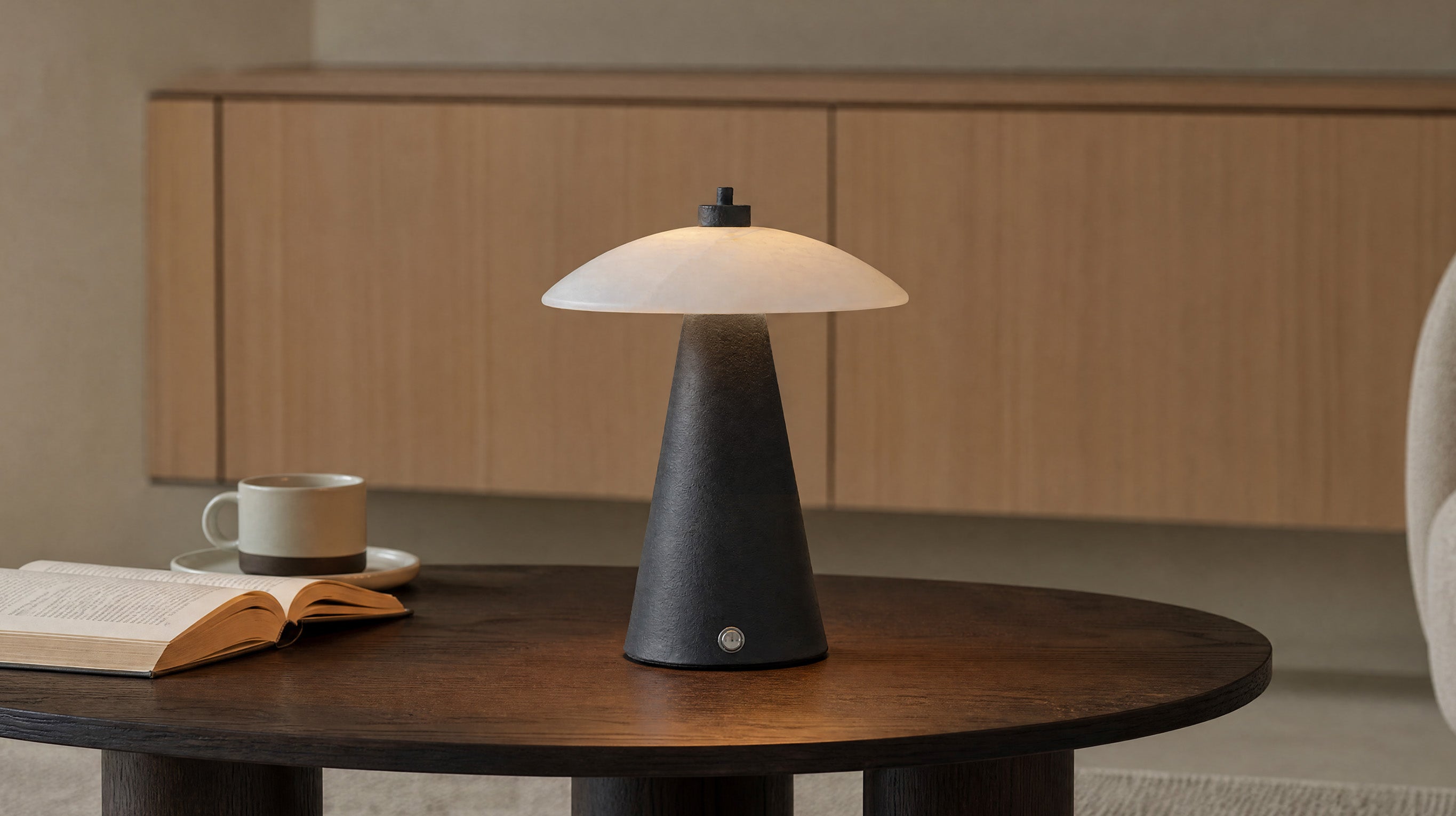 The artamore black textured marble night light featuring a natural marble lampshade and sleek black metal base, glowing warmly in a modern minimalist setting.