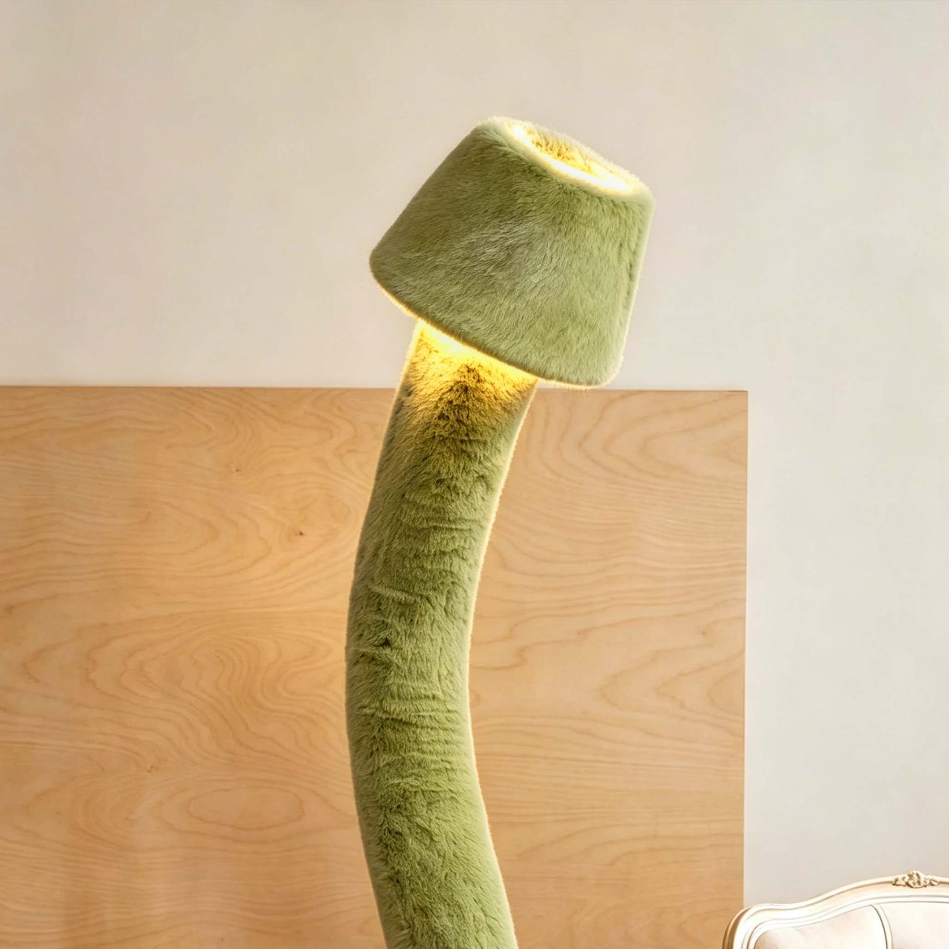 Green plush bendable floor lamp with warm ambient lighting against a wooden wall in a modern interior.