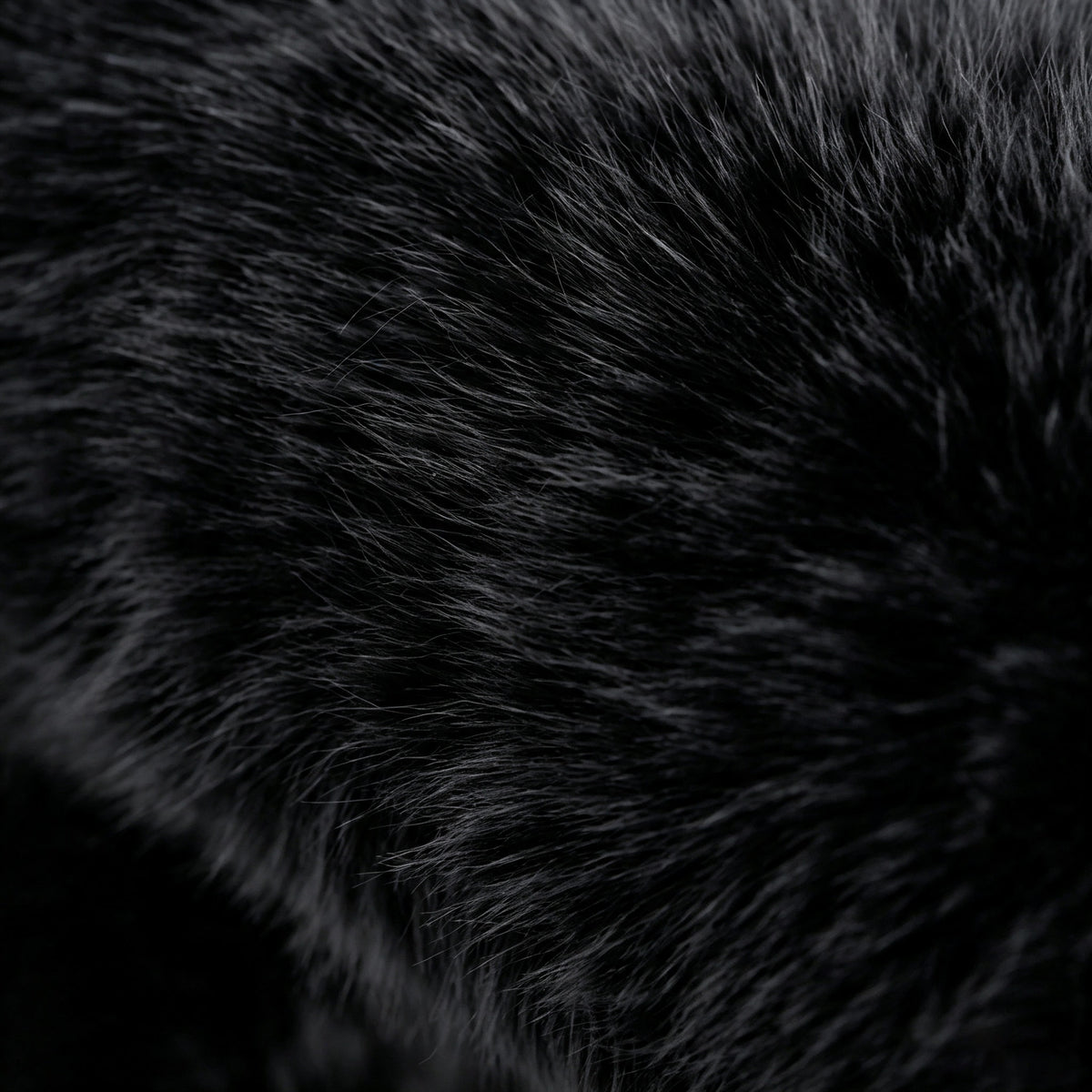 Macro close-up of the dense black plush eco-fur upholstery of the 36.5°C Series Stool.