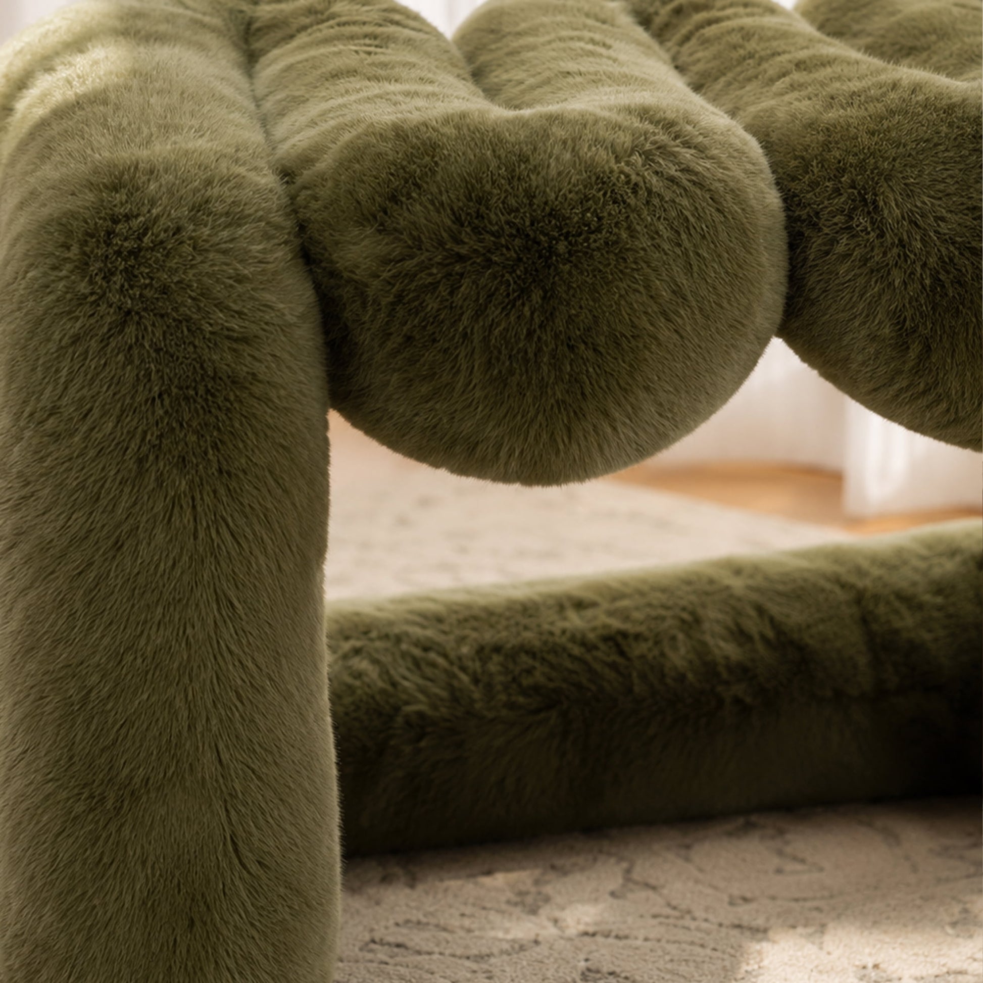 Close-up of the olive green 36.5°C Series Plush Stool showing its curved support and dense eco-fur upholstery.