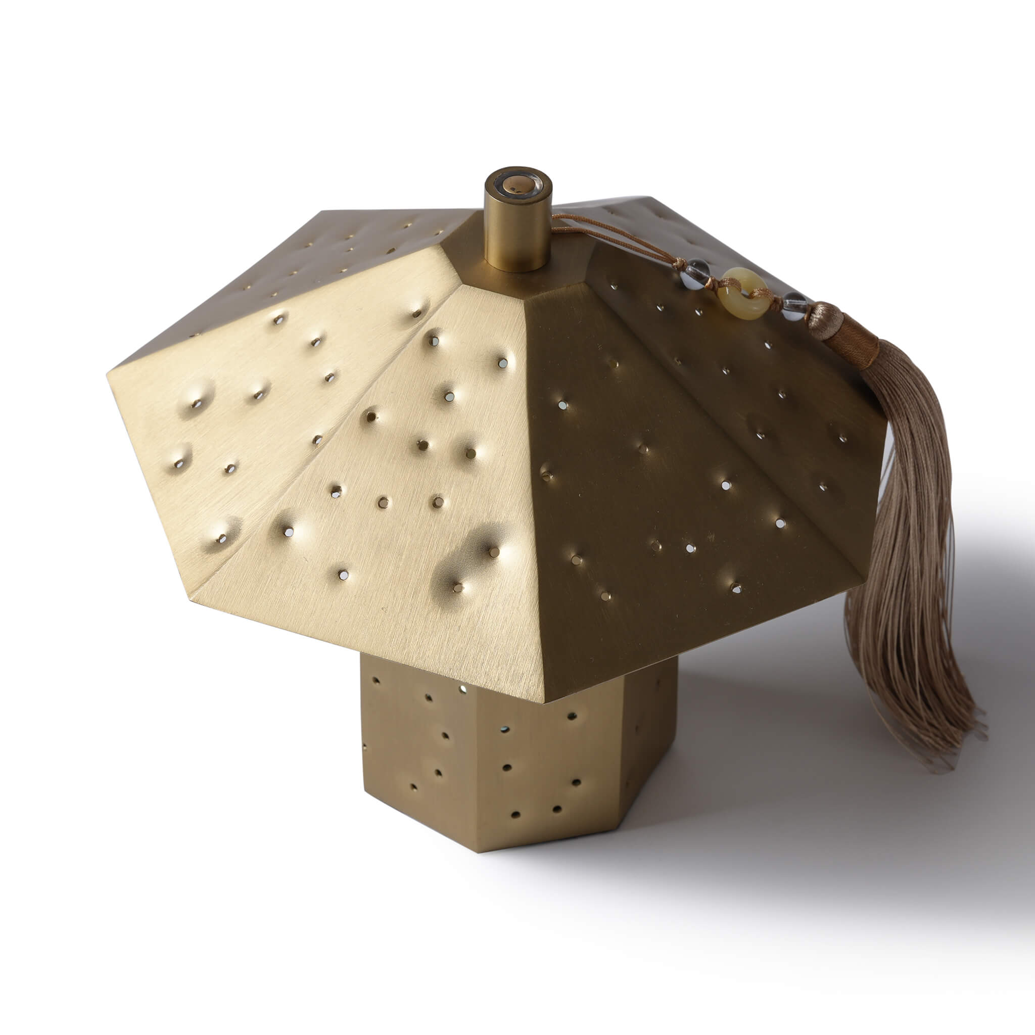 The hammered brass ambient lamp emitting a warm, starry sky light transmission effect in a serene darkened setting.