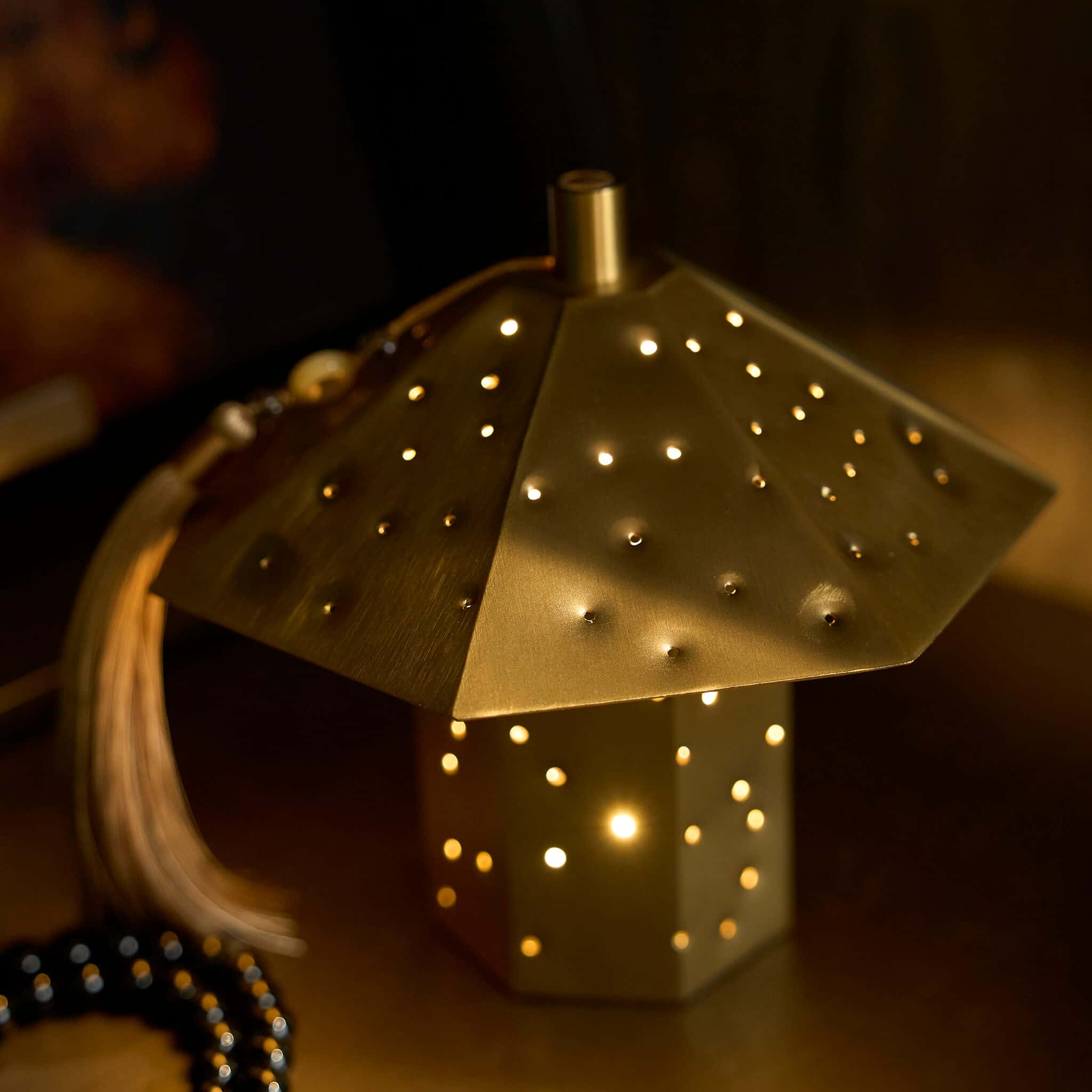 The timeless brushed metal ambient lamp enriching a warm modern organic living room space alongside understated ceramics.