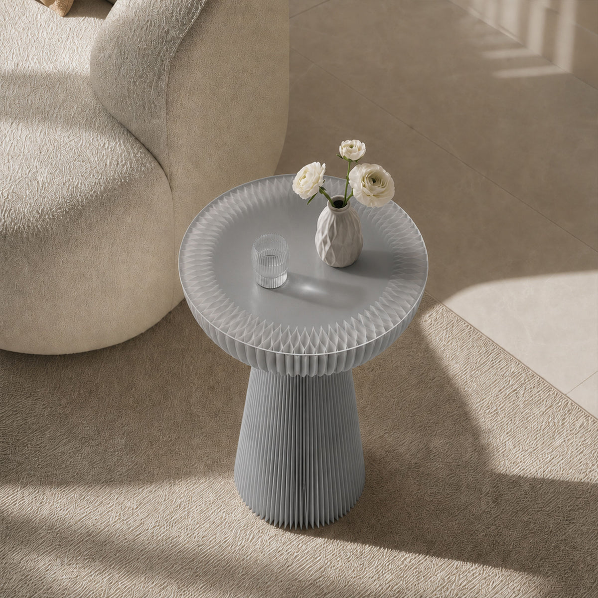 Grey Bouquet Side Table C with a frosted acrylic tabletop styled with white flowers beside a curved sofa.