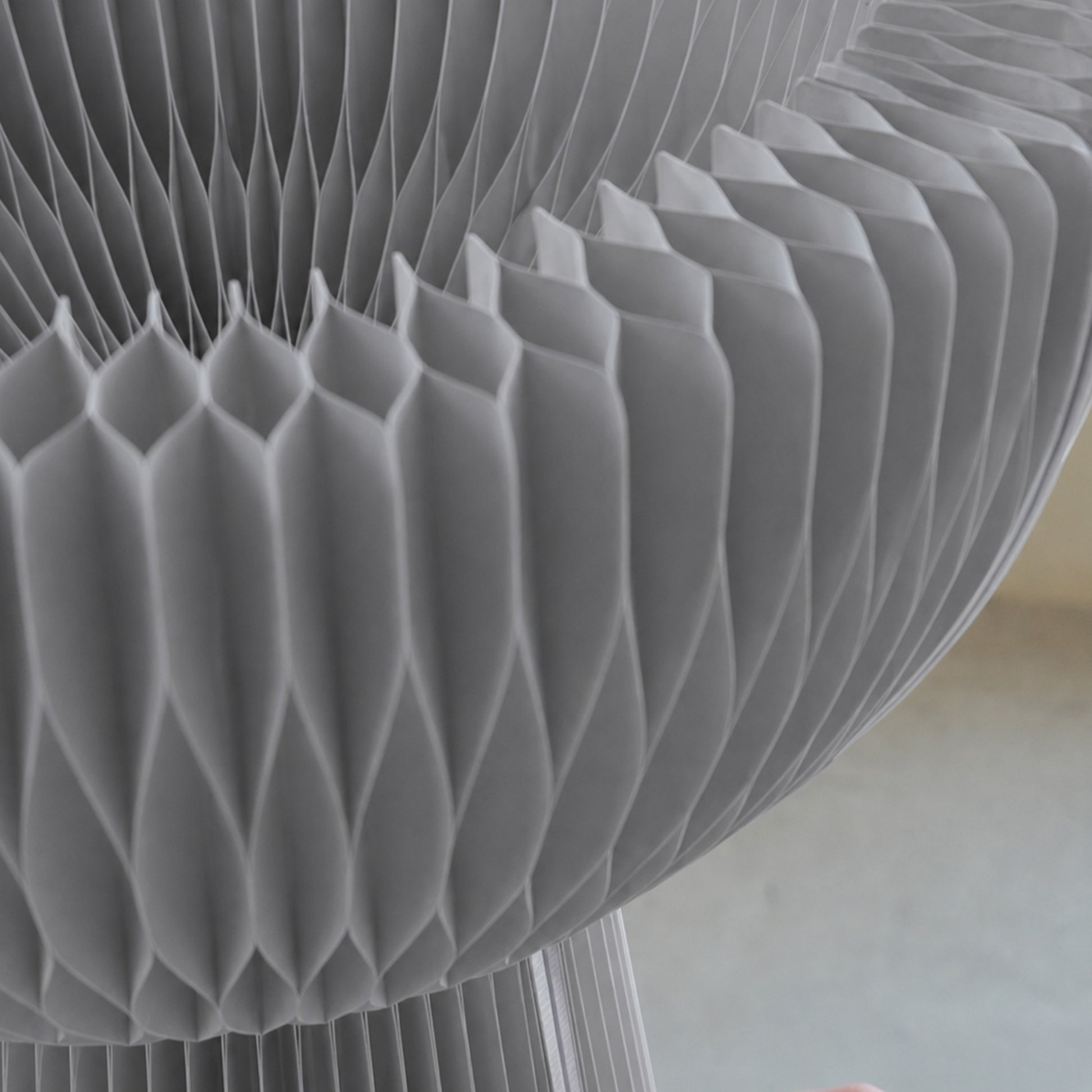 Close-up of the grey Bouquet Side Table C showing its hexagonal honeycomb paper structure and layered folded cells.