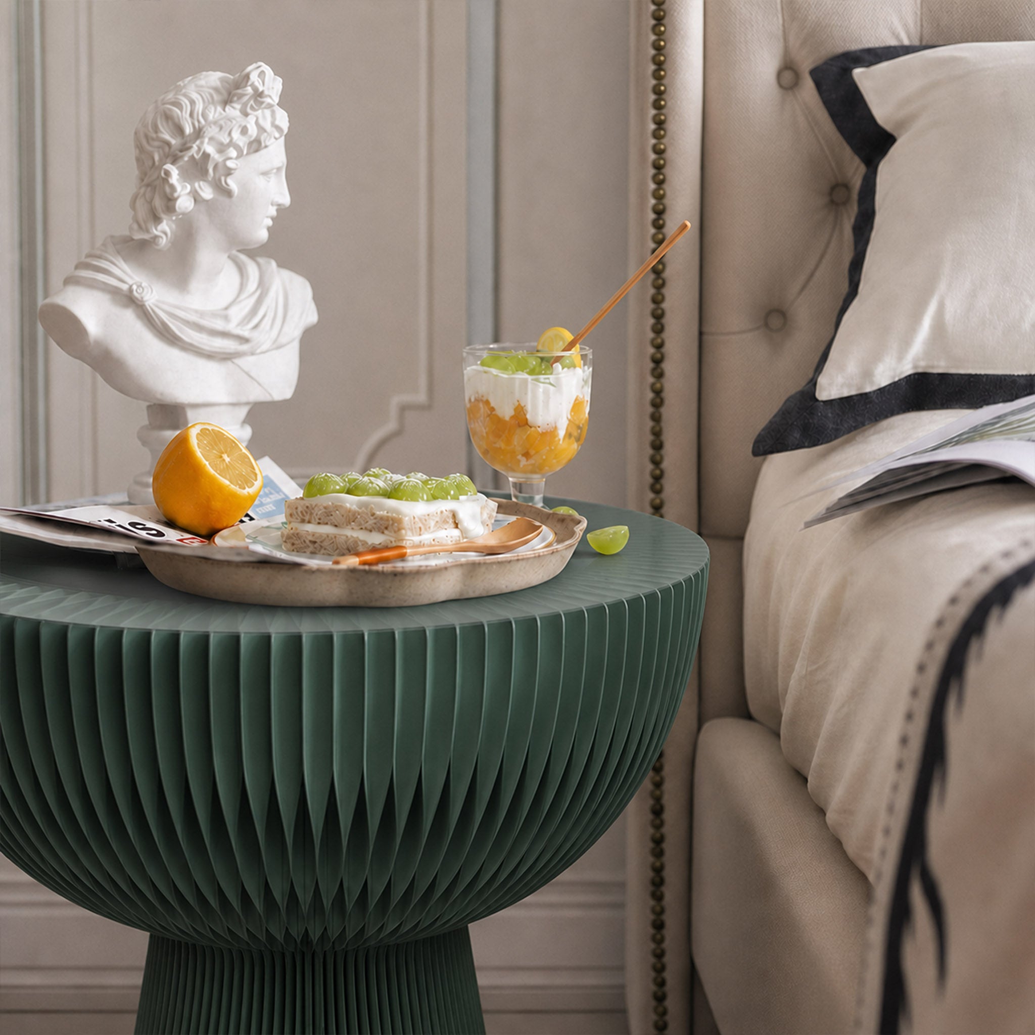 Pine green Bouquet Side Table C used as a tall bedside table with drinks and dessert beside an upholstered bed.