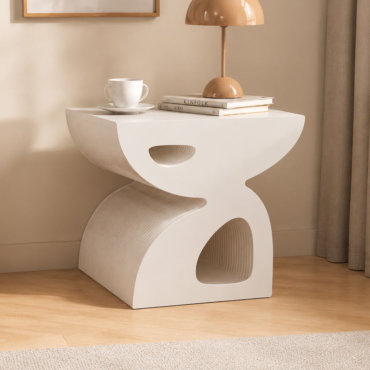 Large white BUTTERFLY honeycomb paper side table styled with books, a cup and a dome table lamp in a warm modern interior.