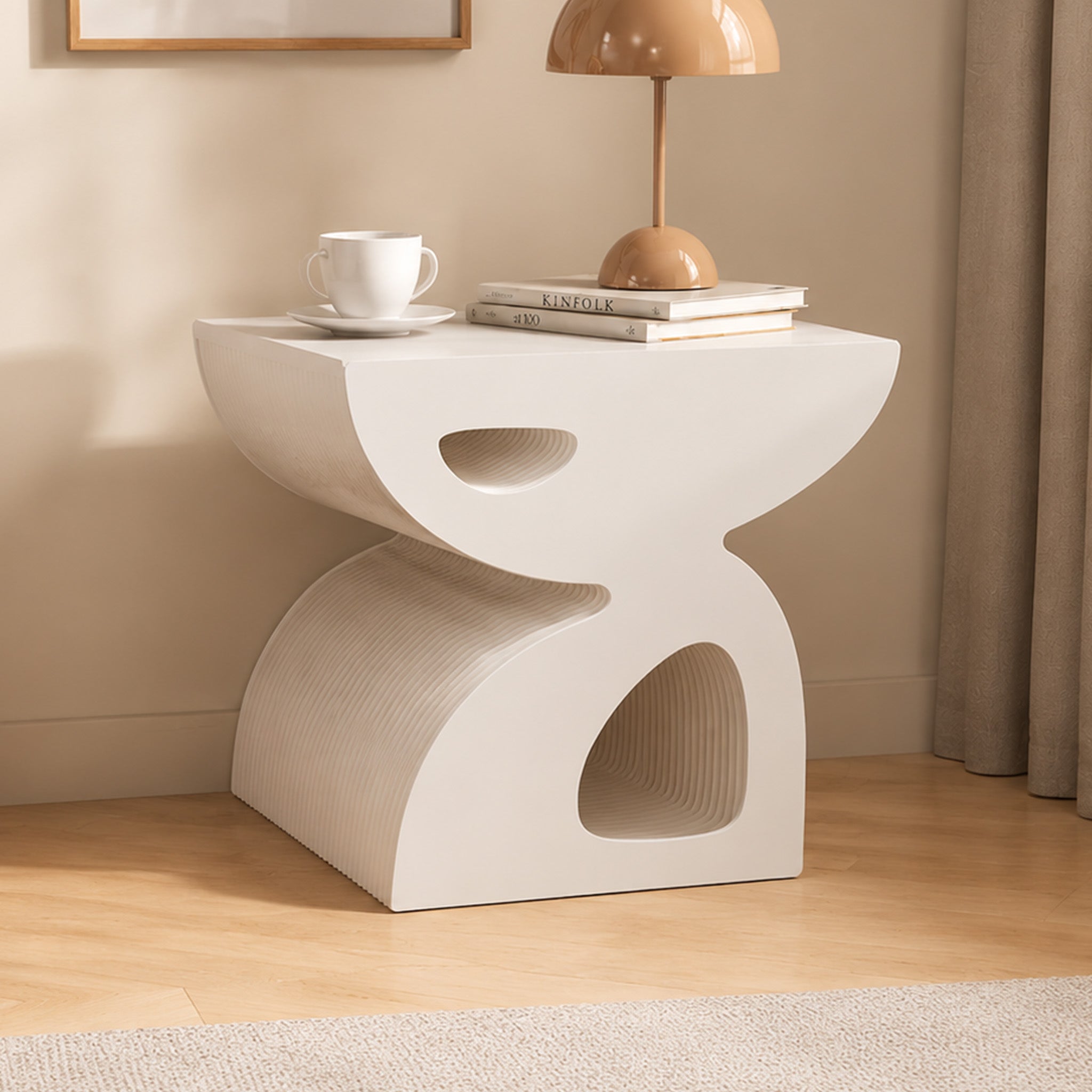 Large white BUTTERFLY honeycomb paper side table styled with books, a cup and a dome table lamp in a warm modern interior.