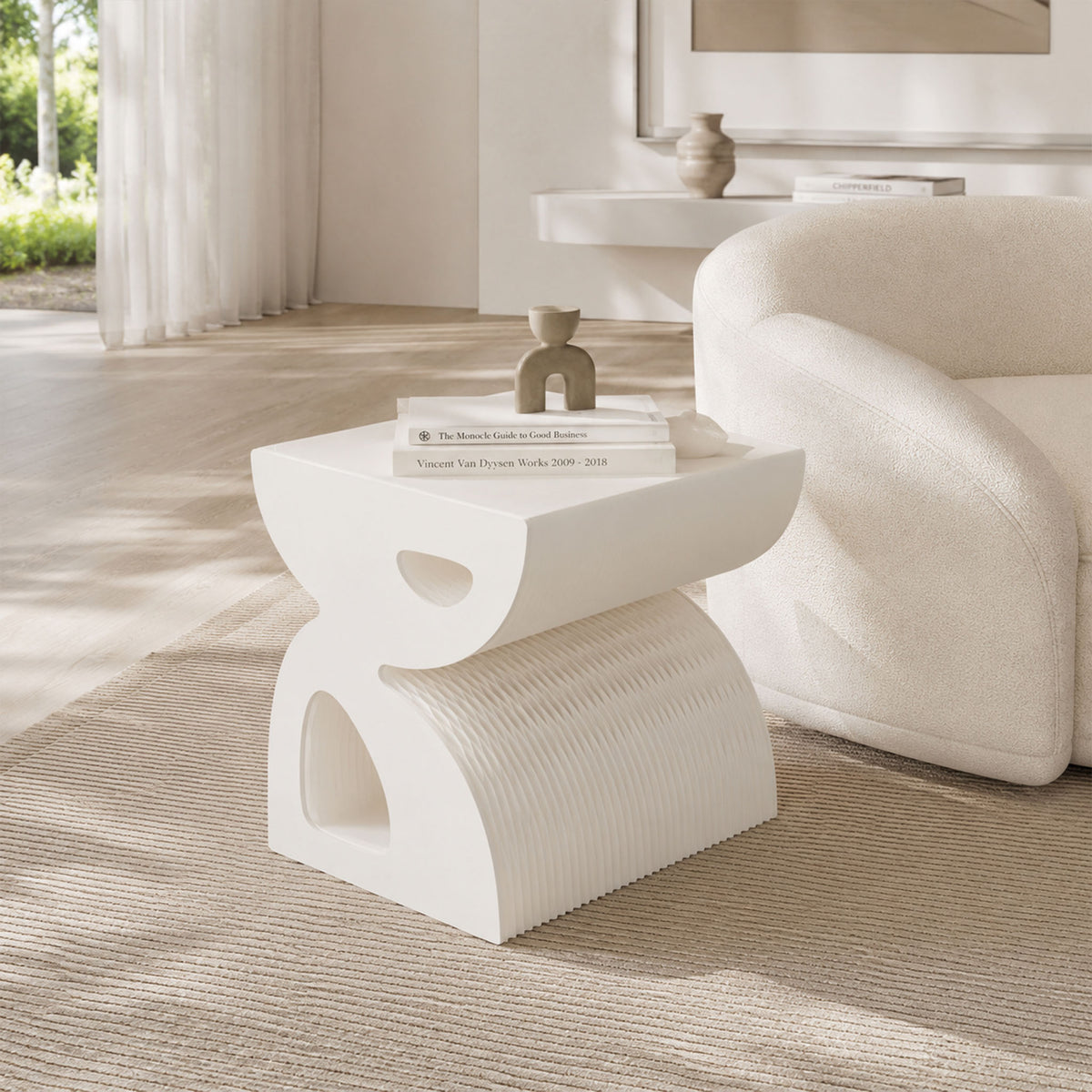 Small white BUTTERFLY sculptural side table with a honeycomb paper body styled beside a curved sofa in a contemporary living room.