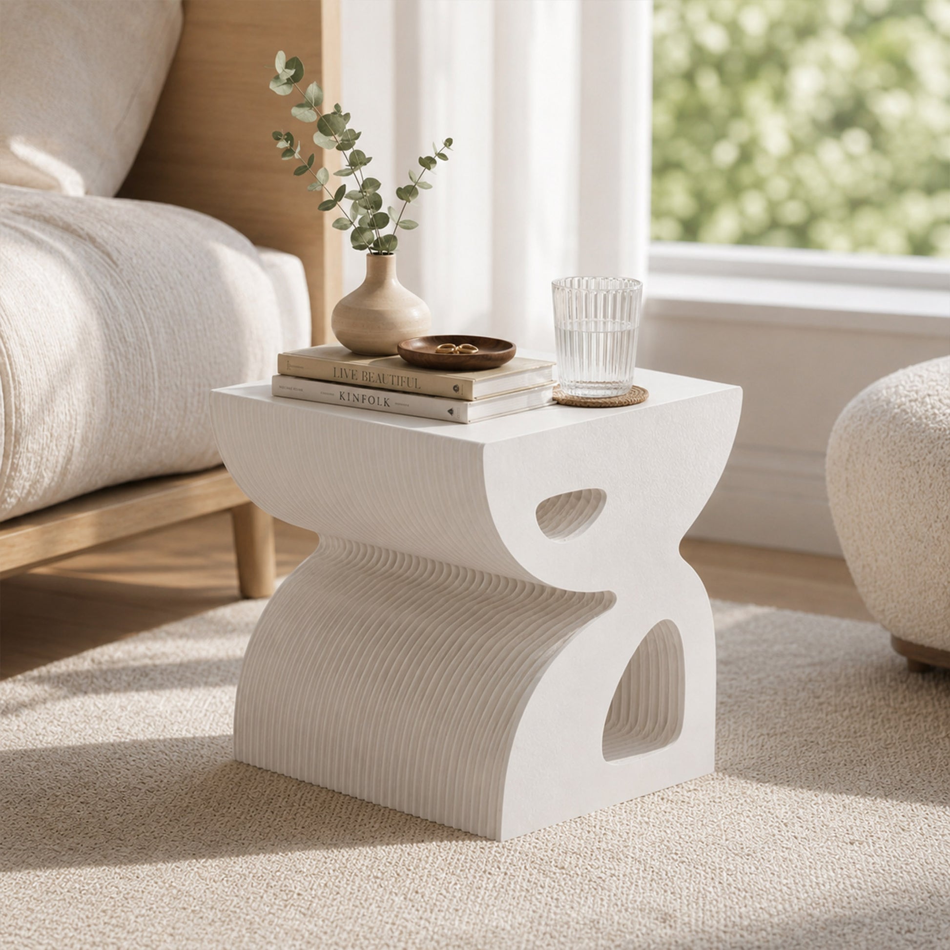 Small white BUTTERFLY honeycomb paper side table styled beside a sofa with books, a ceramic vase and a drinking glass.