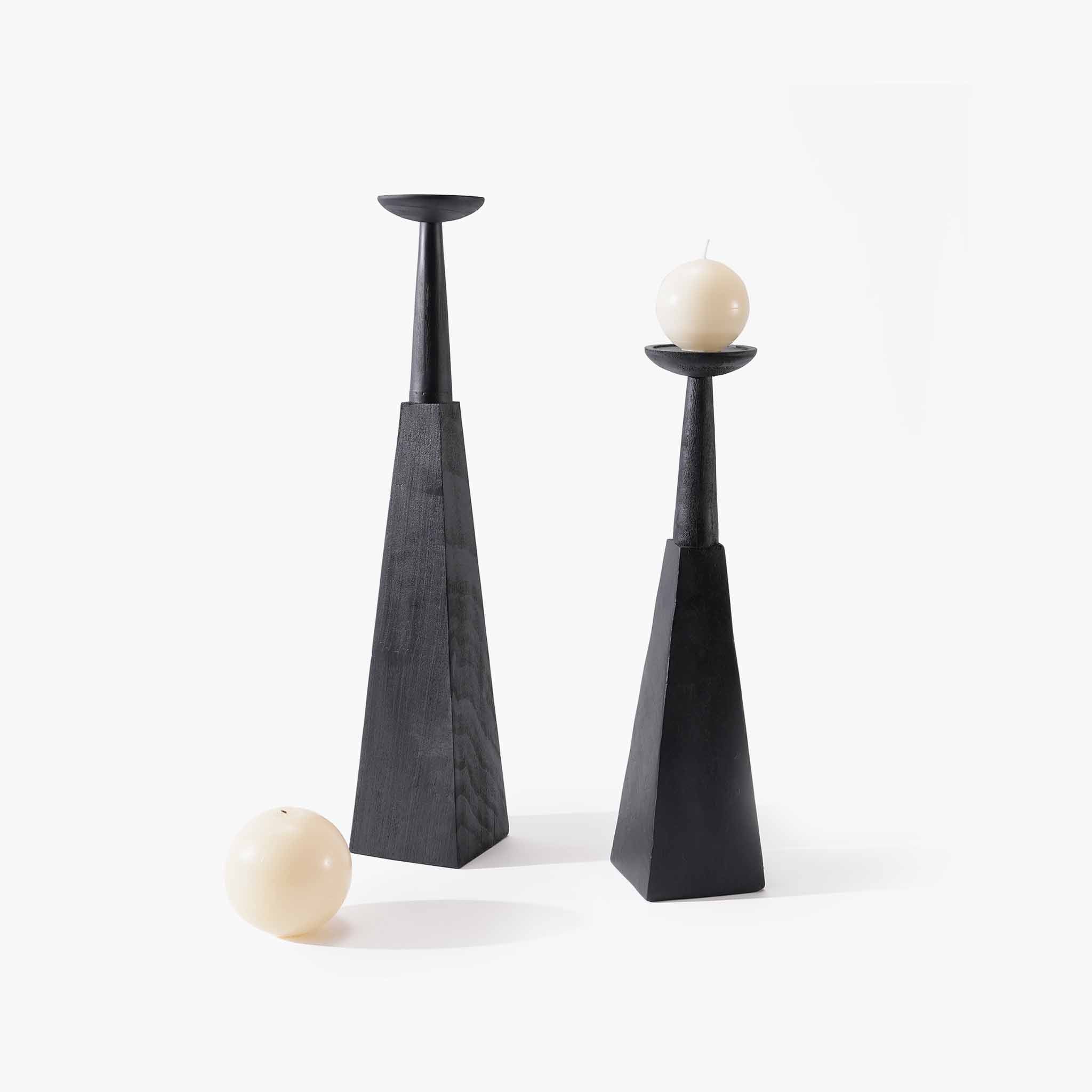 Set of two geometric black wood floor candle holders in varying heights with beige candles