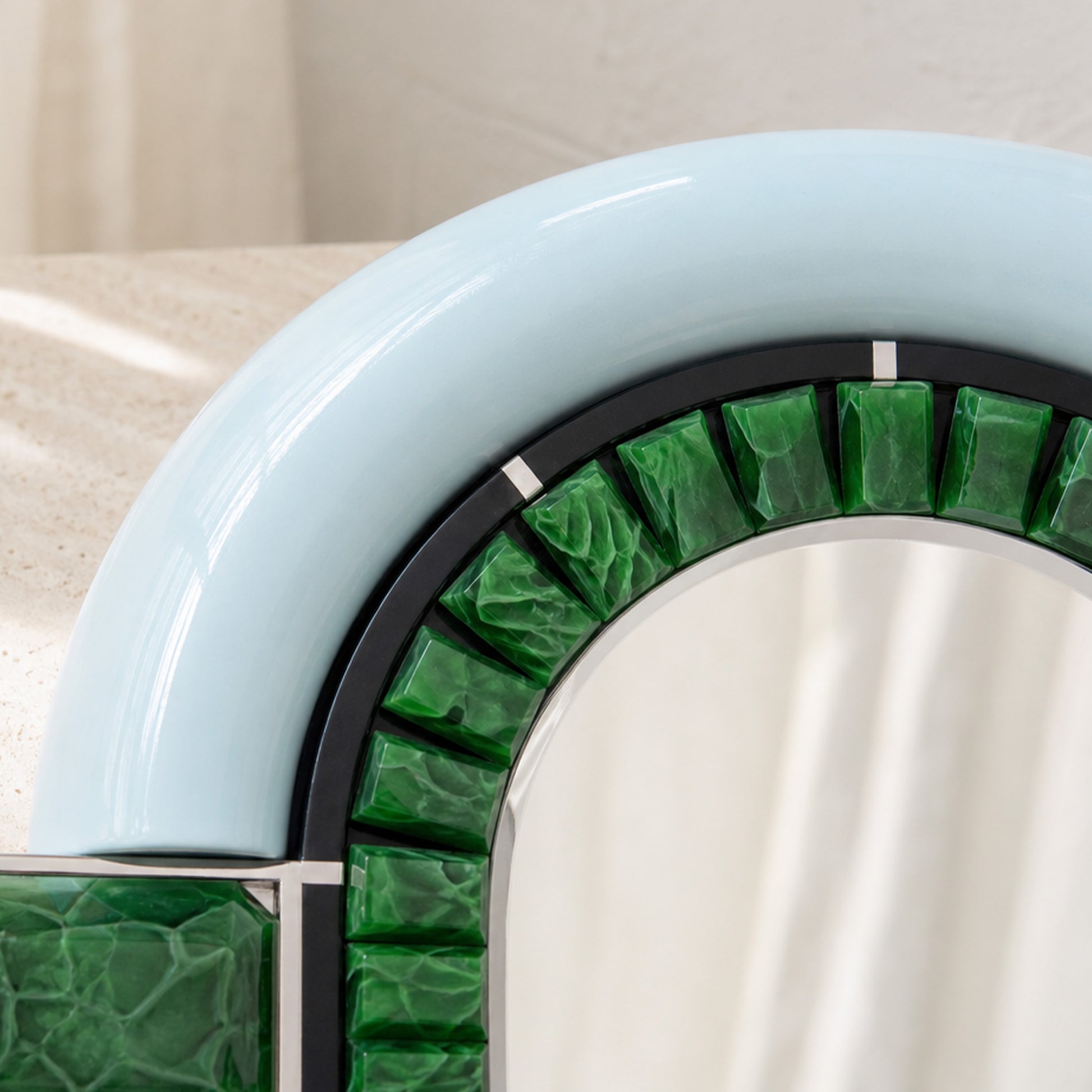 Close-up of the arched frame on Artamore Celebrity Mirror with emerald recycled glass and pale blue finish.