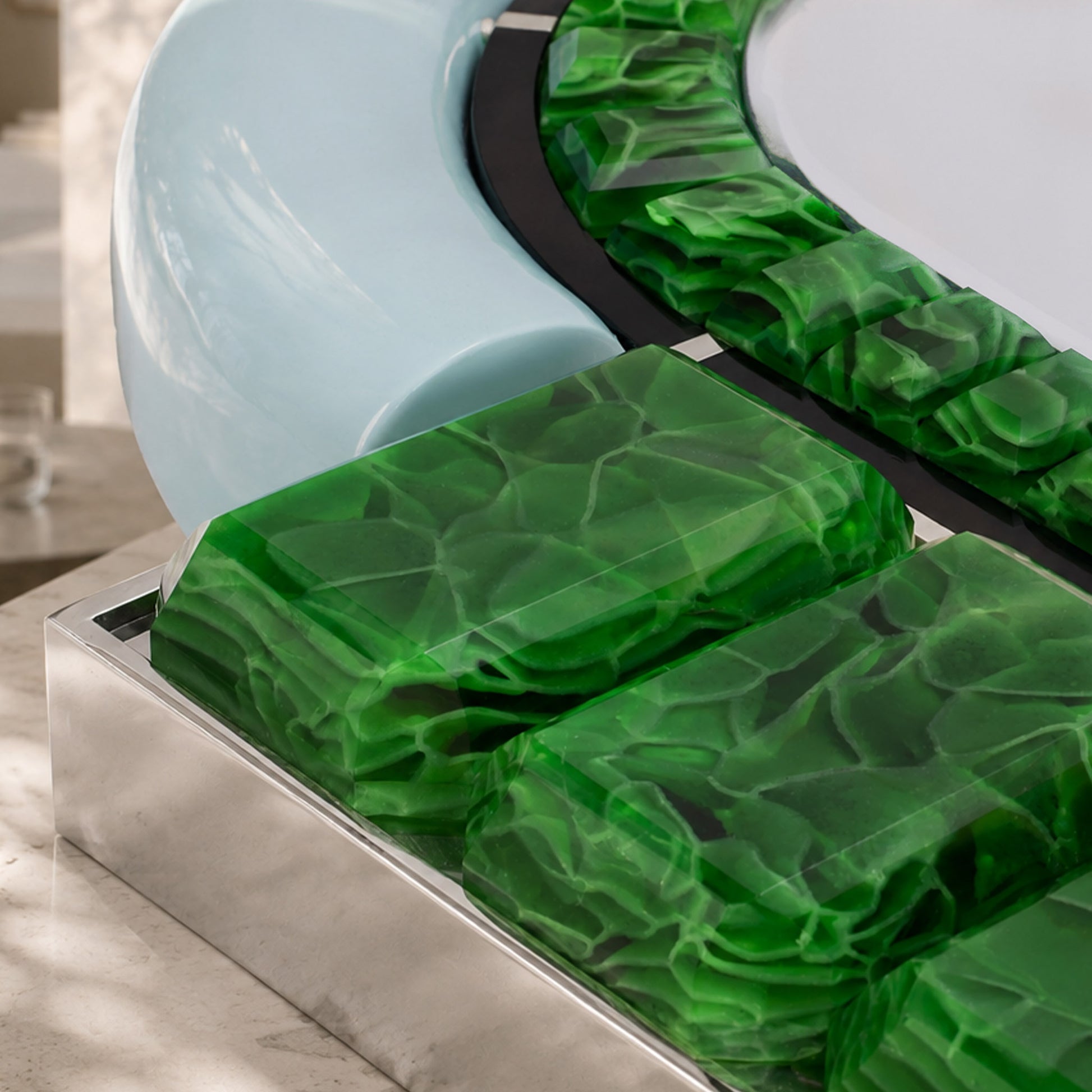 Detail of Artamore Celebrity Mirror featuring green recycled glass, chrome trim, and a soft blue accent.