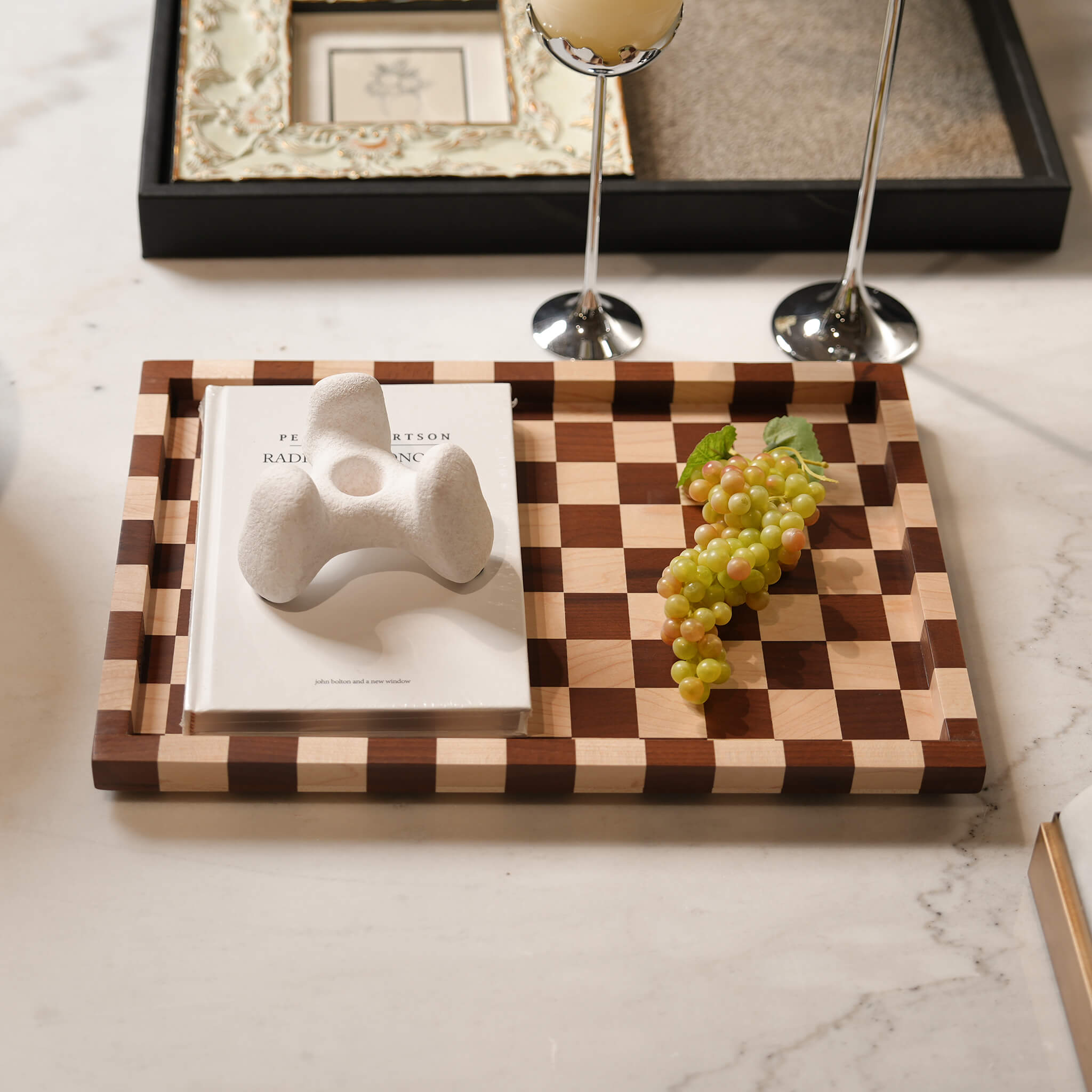 Walnut checkerboard serving tray styled elegantly on a modern marble coffee table with a book and decor