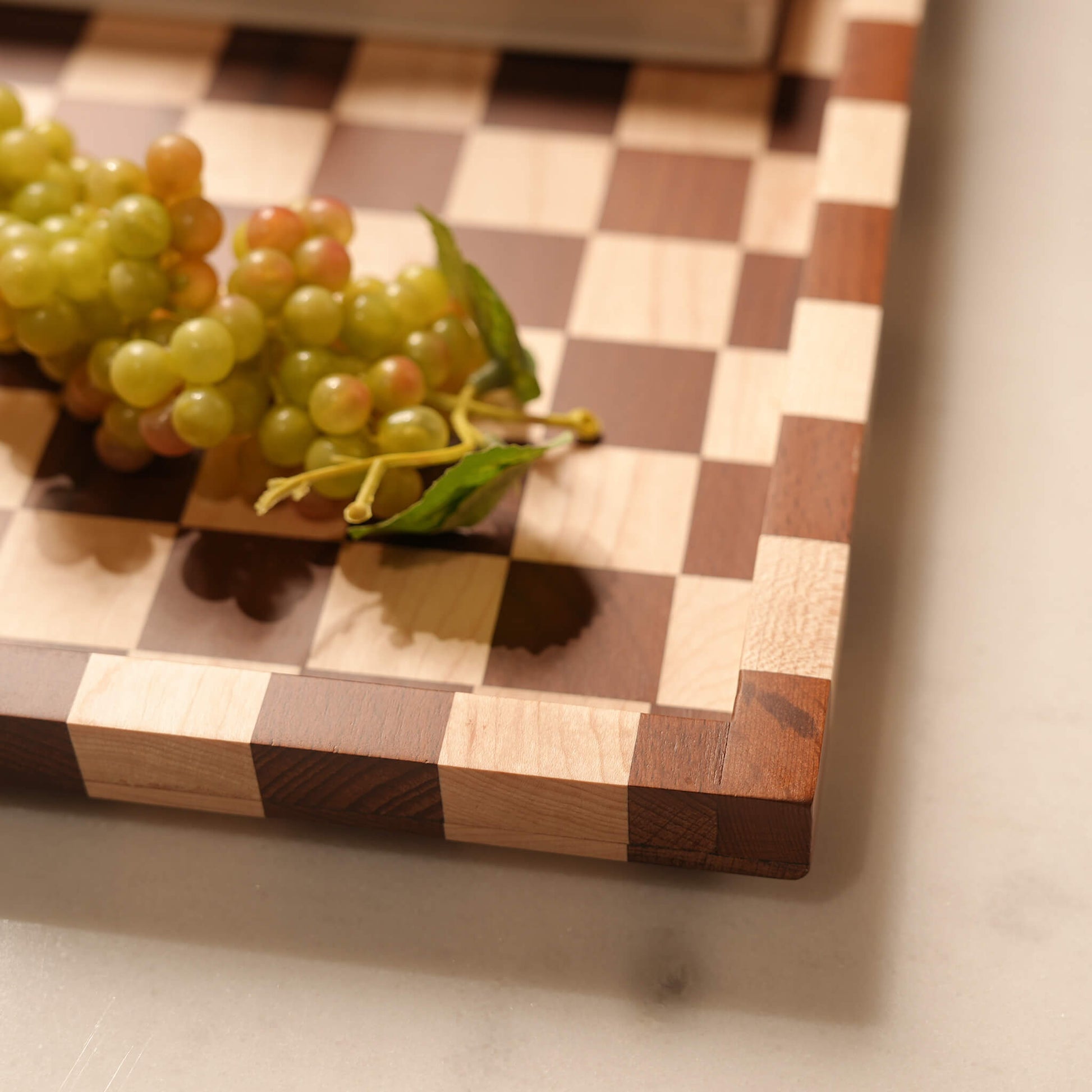 Detailed view of grapes resting on the smoothly polished, exquisite surface of the two-tone wood serving tray