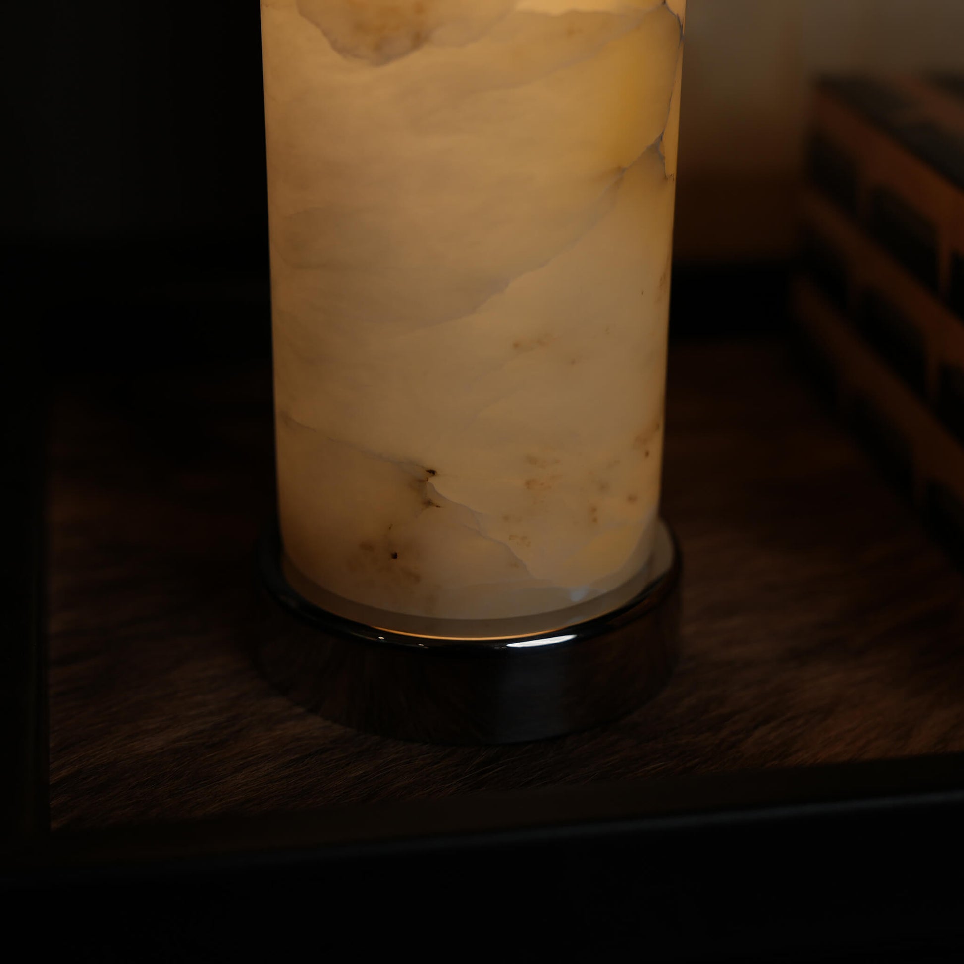 Close-up of the illuminated marble pillar base and metal fittings, demonstrating premium craftsmanship and atmospheric lighting.