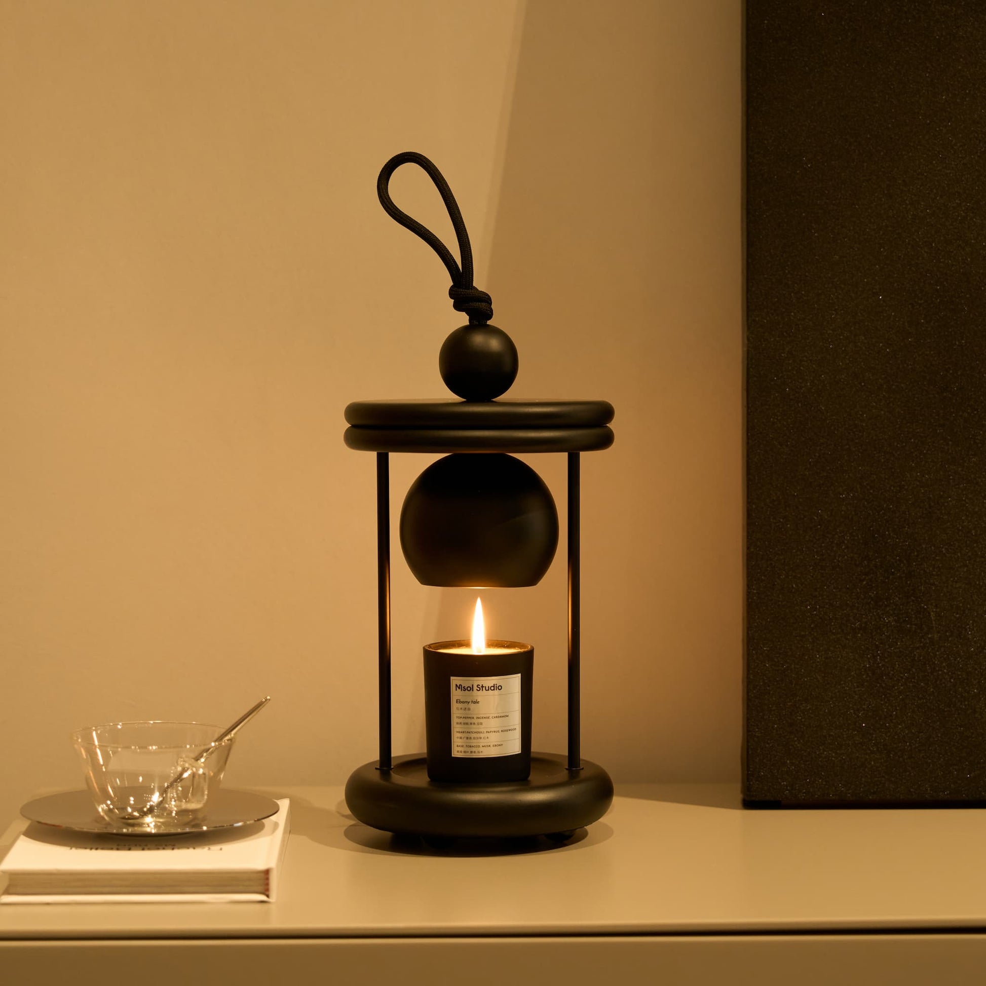 The minimalist Dawn candle warmer lamp providing a warm glow on a modern living room side table.