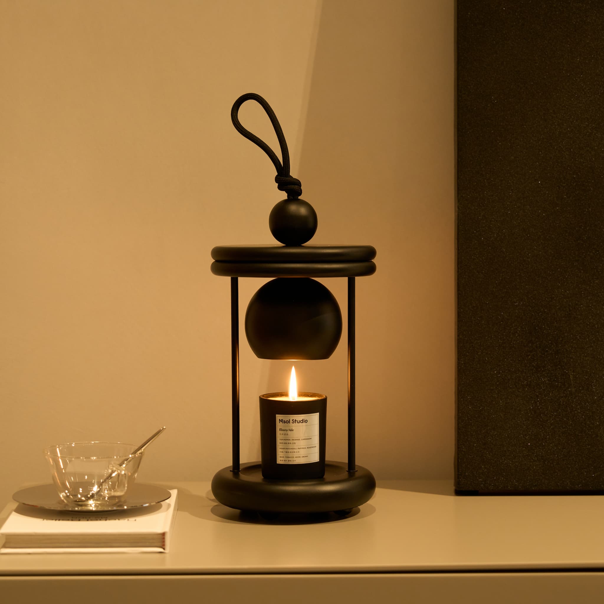 The minimalist Dawn candle warmer lamp providing a warm glow on a modern living room side table.