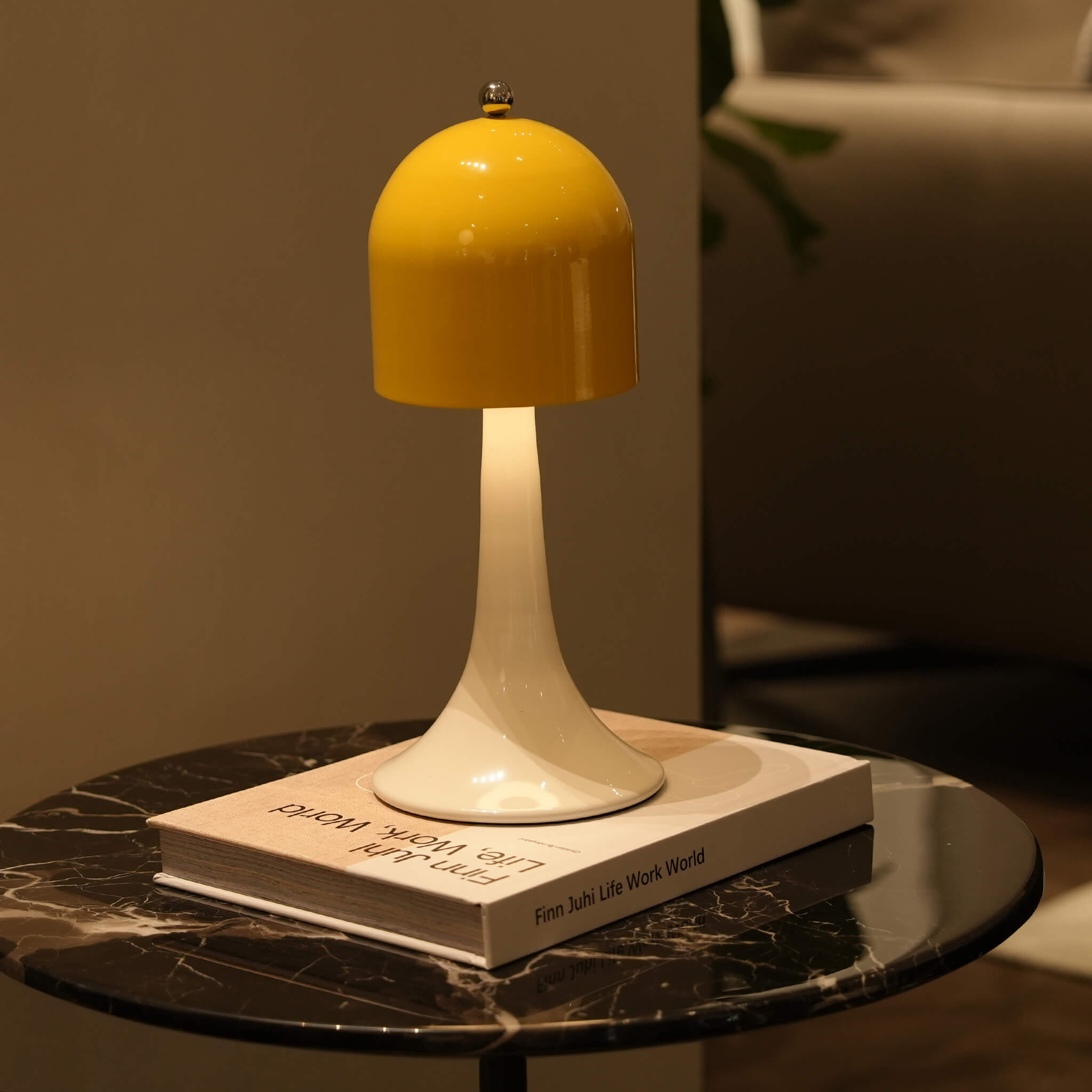 The elegant yellow cordless touch table lamp styled on a chic dark marble side table in a contemporary European living room.