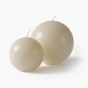 Two sizes of the sculptural egg-shaped scented candle in a minimalist cream finish , showing the large and small variations