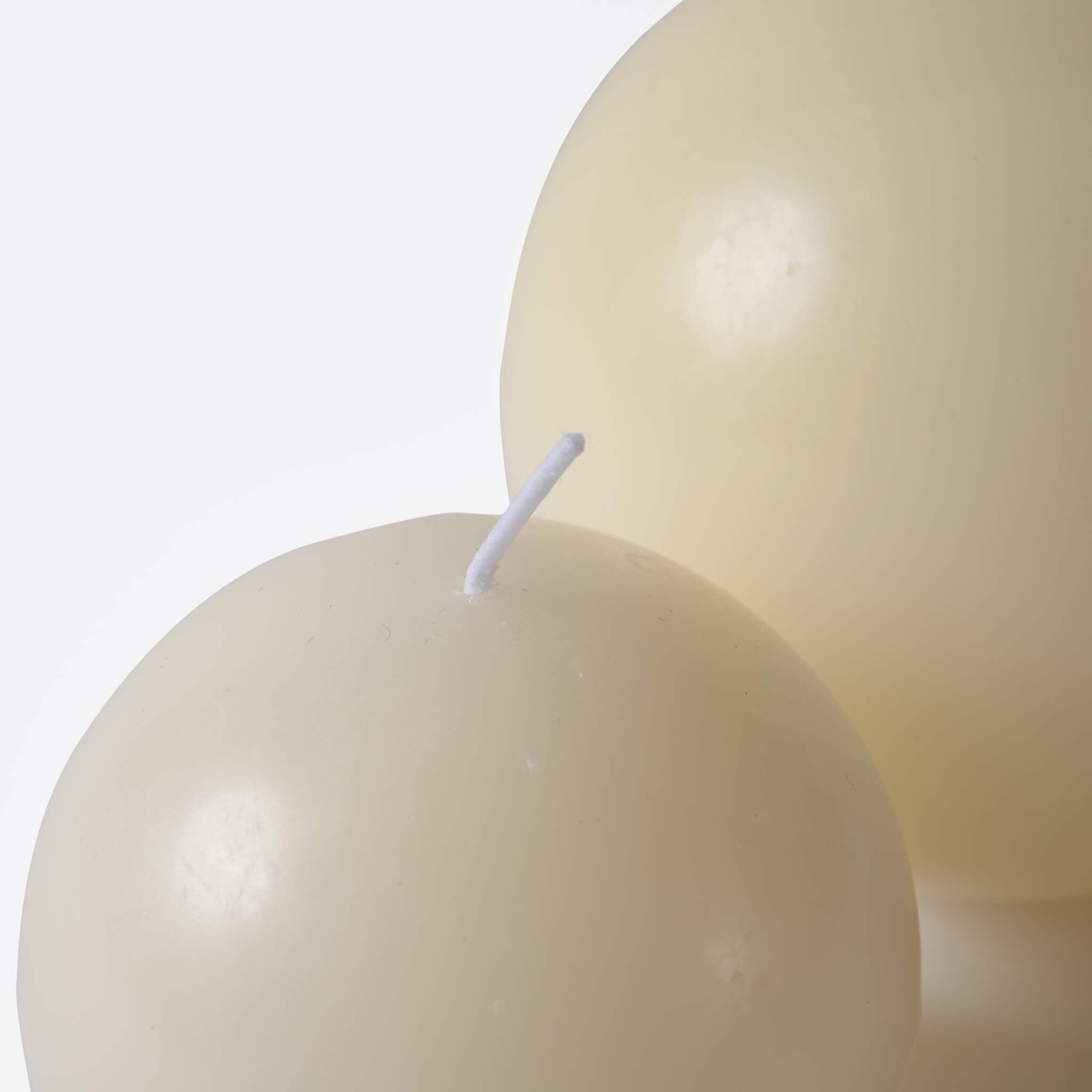 Macro detail of the unlit wick on the cream-colored egg-shaped scented candle, highlighting its smooth texture