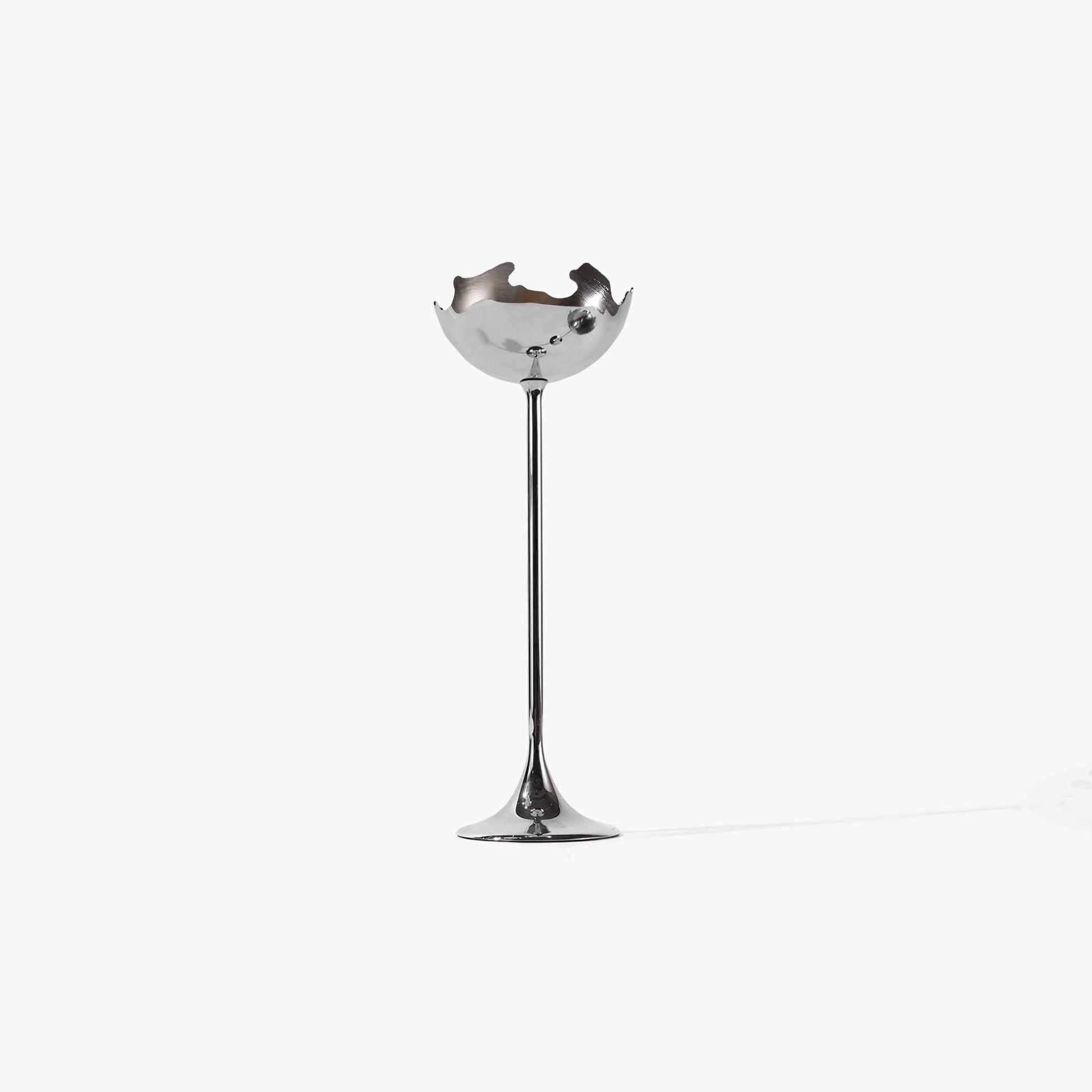Detail of the solid metal sculptural candlestick showing its fluid lines and raw silver edges.
