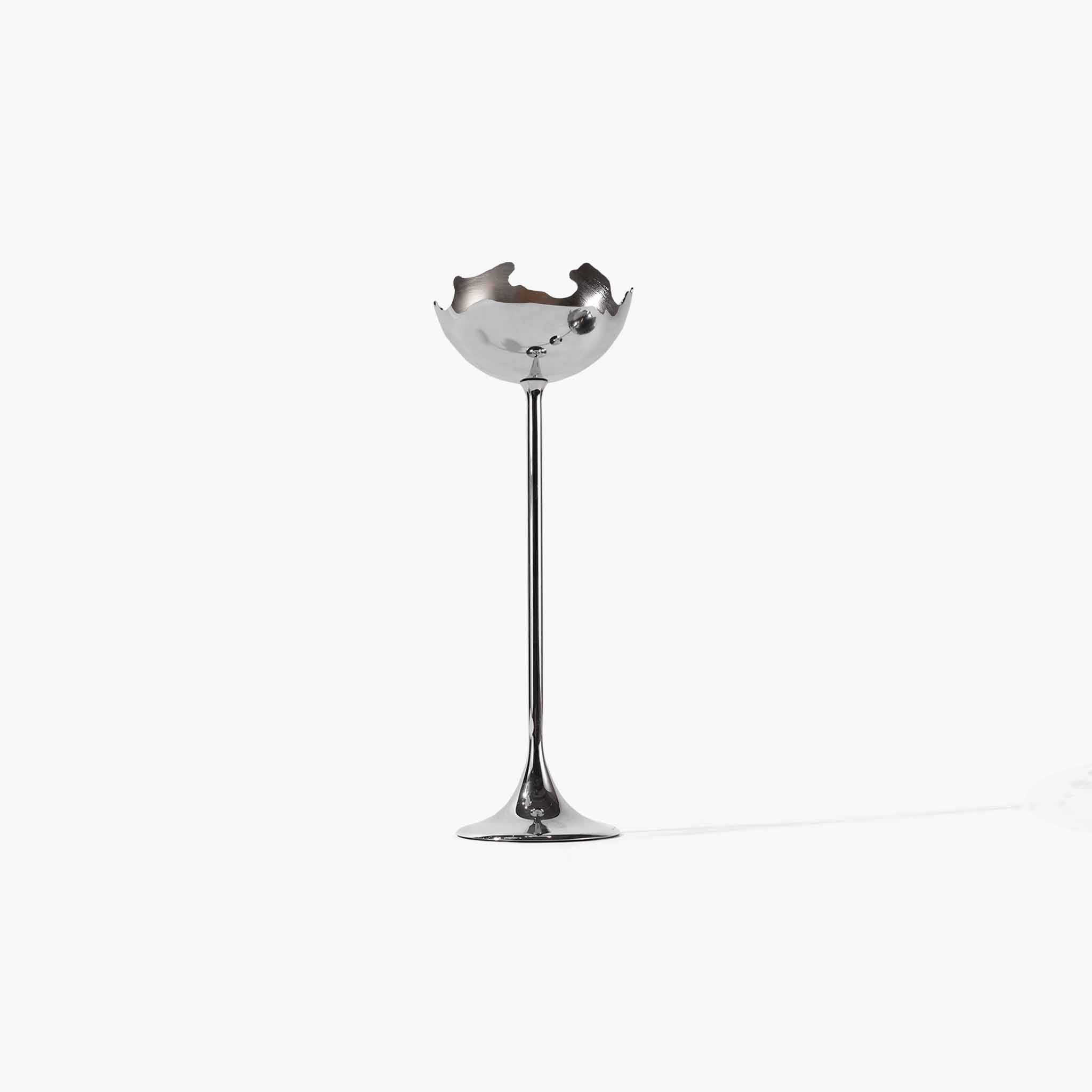 Detail of the solid metal sculptural candlestick showing its fluid lines and raw silver edges.