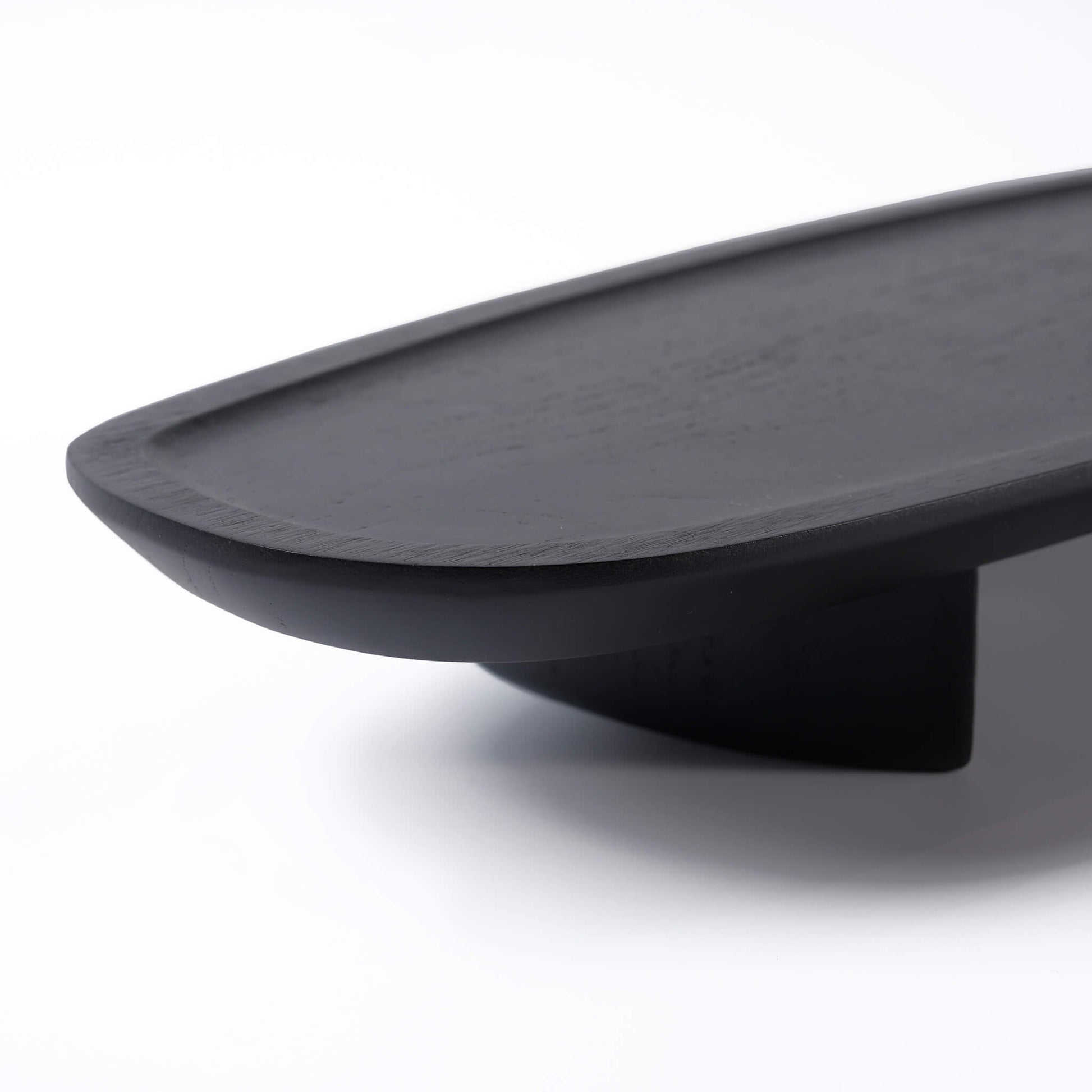 Close-up of the smooth touch and rounded edges of the black wooden tray, highlighting the natural wood grain
