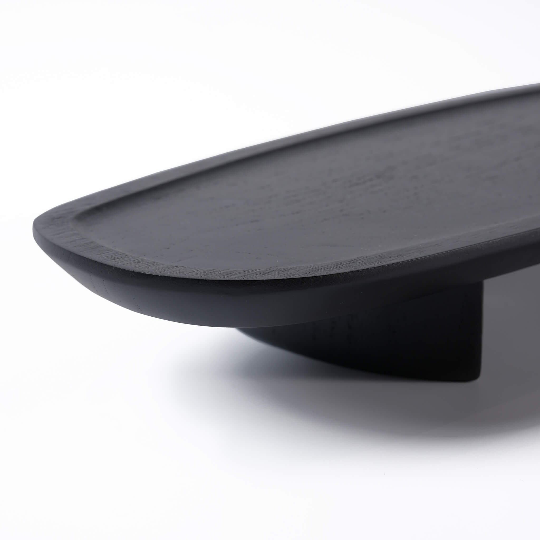 Close-up of the smooth touch and rounded edges of the black wooden tray, highlighting the natural wood grain