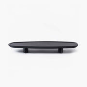 Minimalist black elongated wooden tray with rounded edges, resting on two subtle wooden feet.