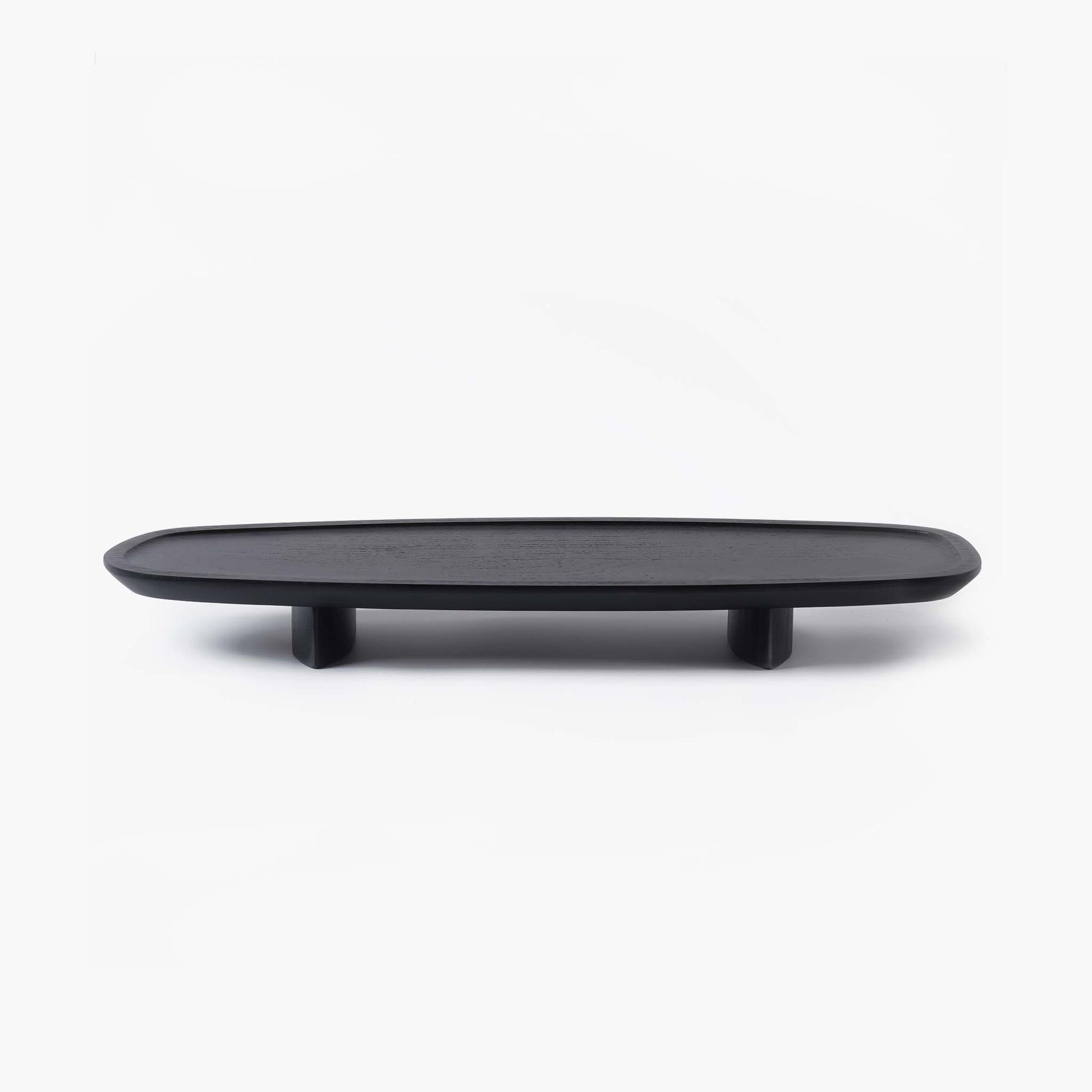 Minimalist black elongated wooden tray with rounded edges, resting on two subtle wooden feet.