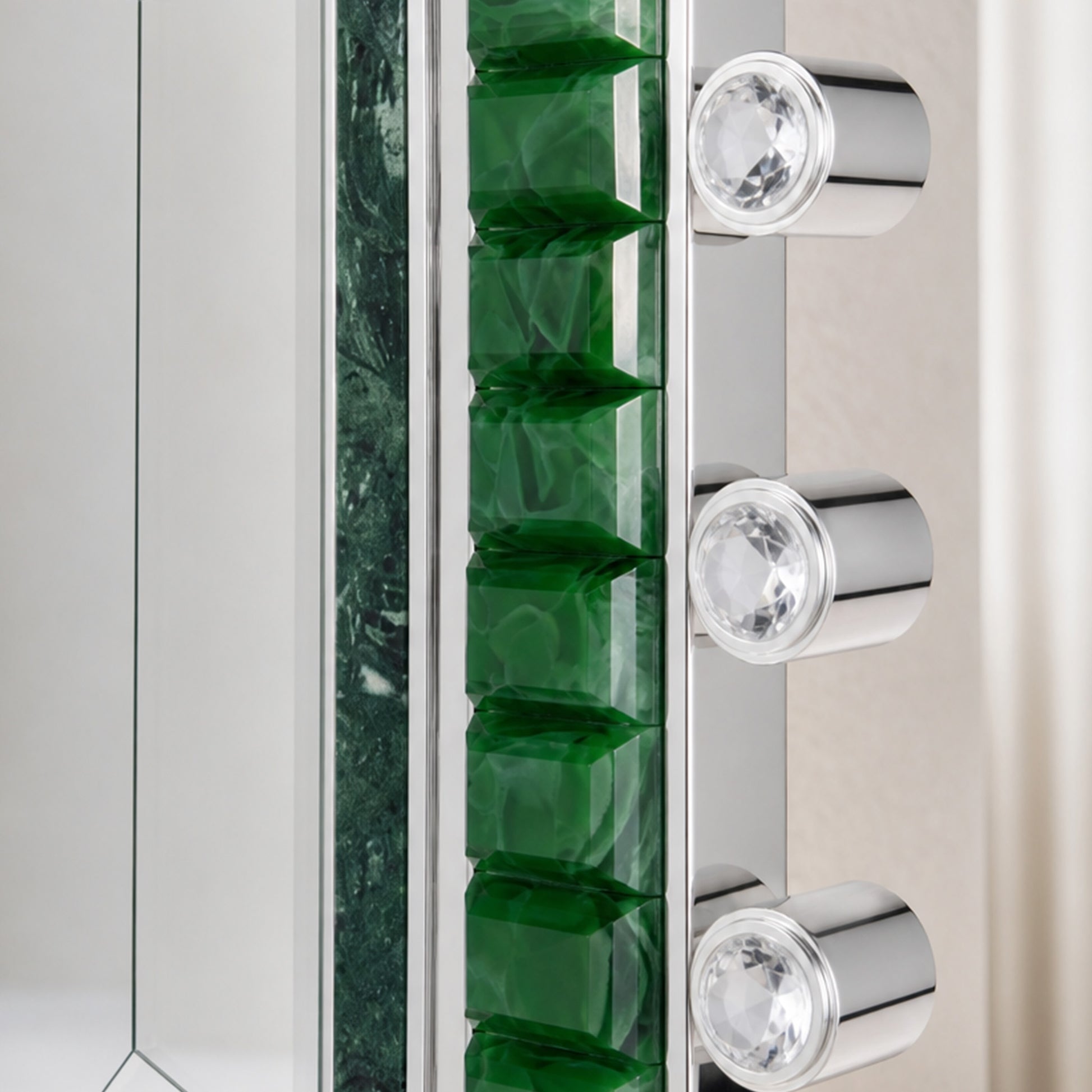 Emerald green glass mirror detail with polished metal edge and crystal hardware accents.