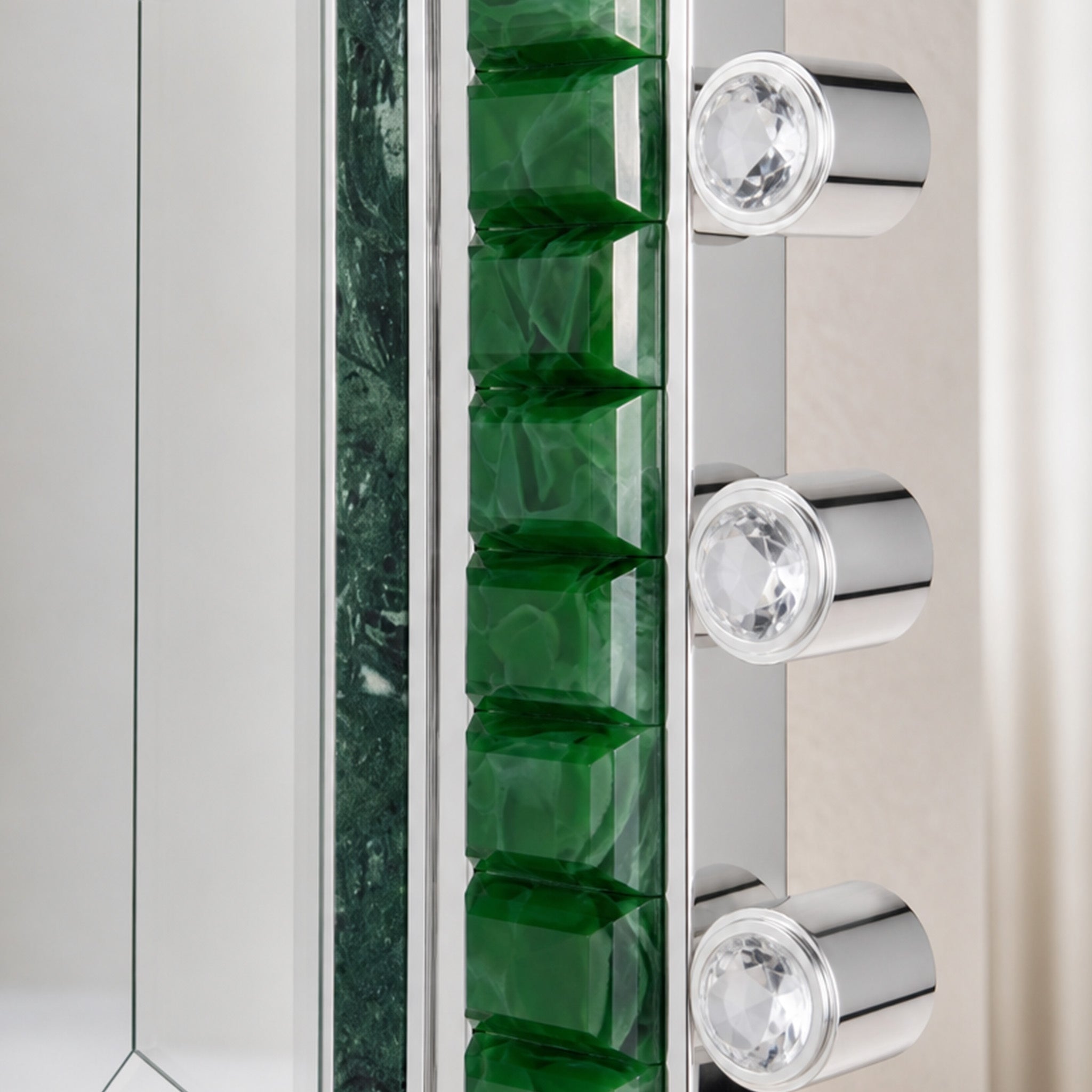 Emerald green glass mirror detail with polished metal edge and crystal hardware accents.