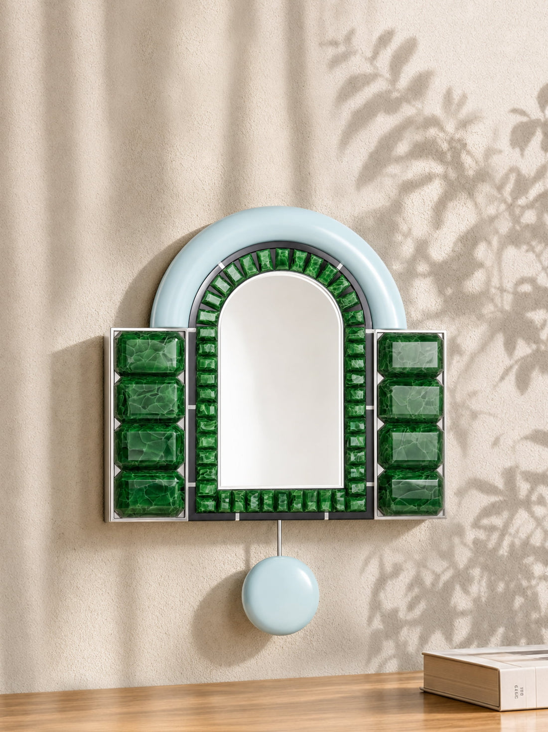 Green recycled glass decorative wall mirror with pale blue details in a sunlit modern interior.