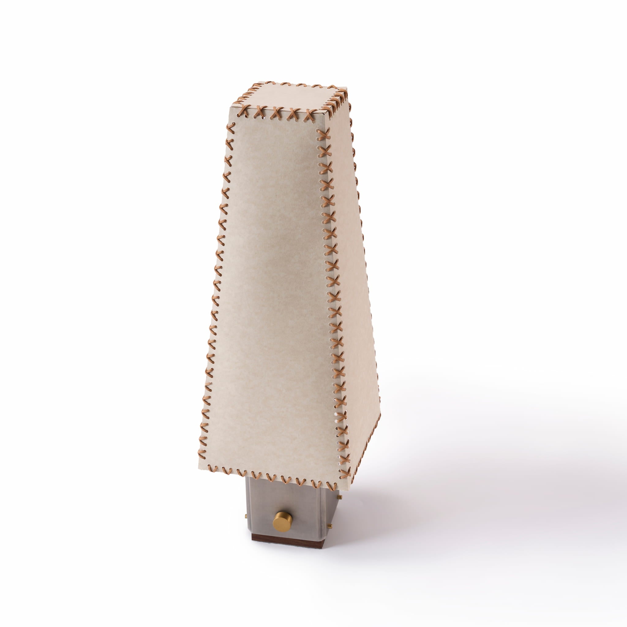 Isometric view of the handmade parchment table lamp showcasing the top leather stitching and geometric silhouette.