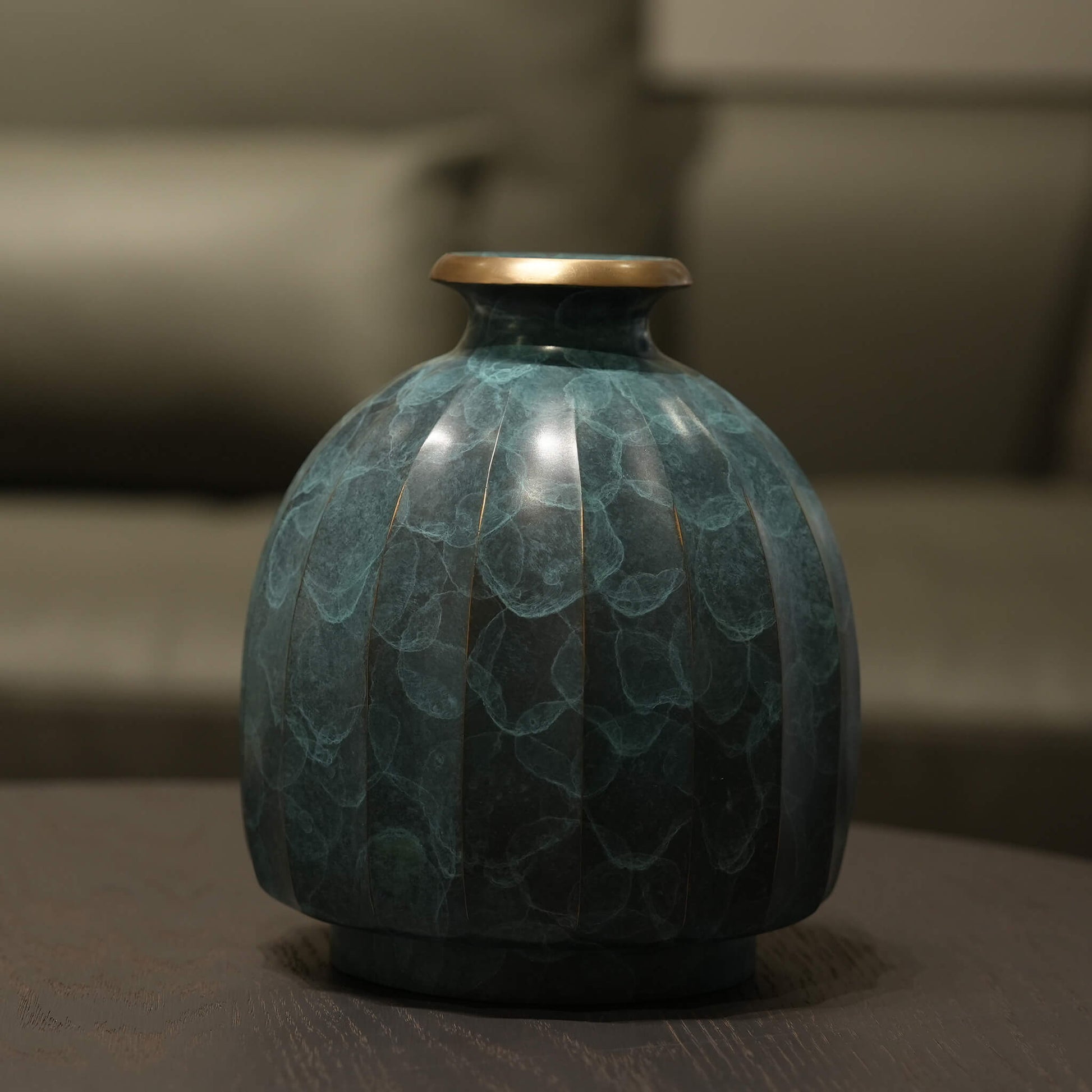 Solid brass vase reflecting subtle ambient light in a serene and elegant entryway.