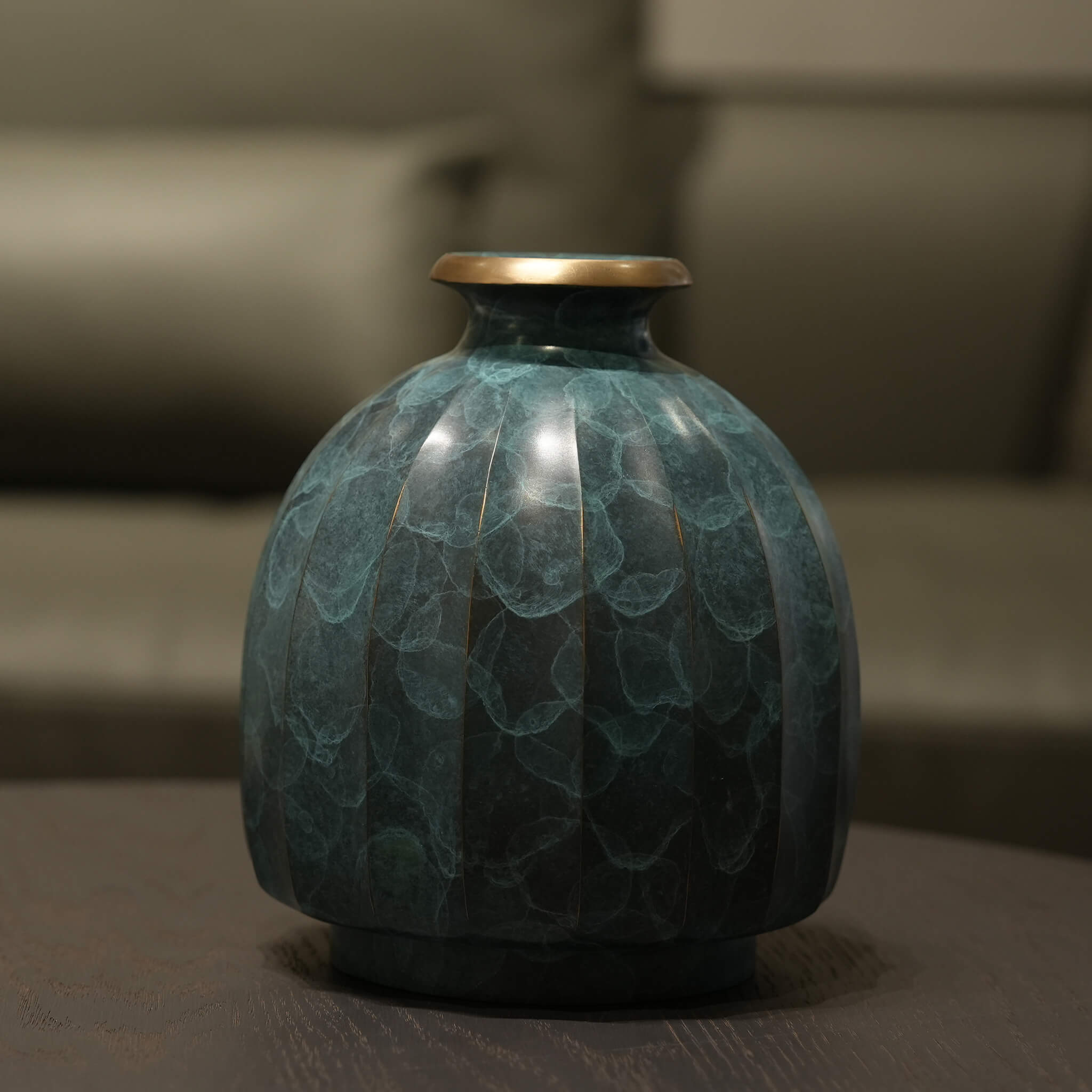 Solid brass vase reflecting subtle ambient light in a serene and elegant entryway.