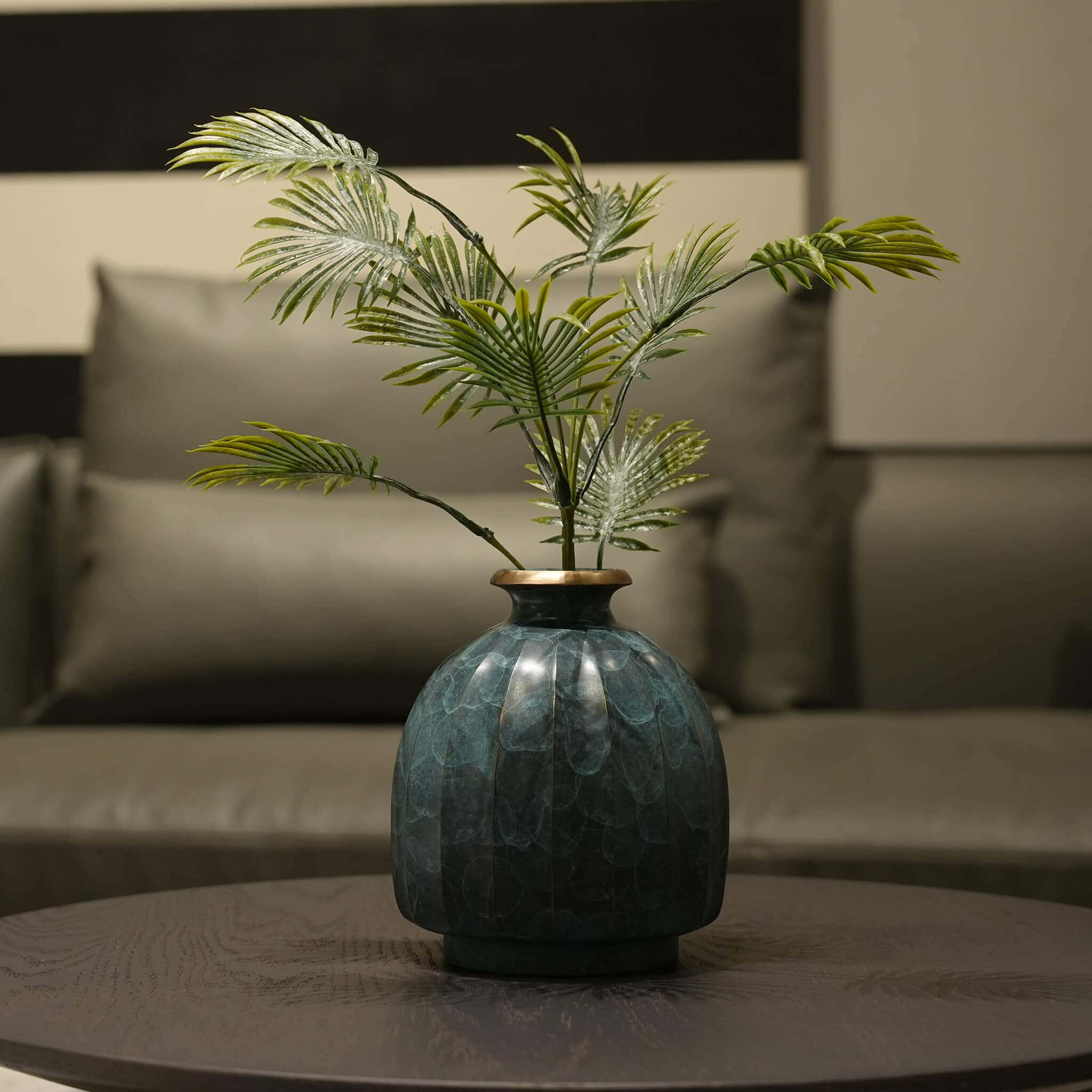 Elegant metal flower vessel styled in a minimalist living room setting.