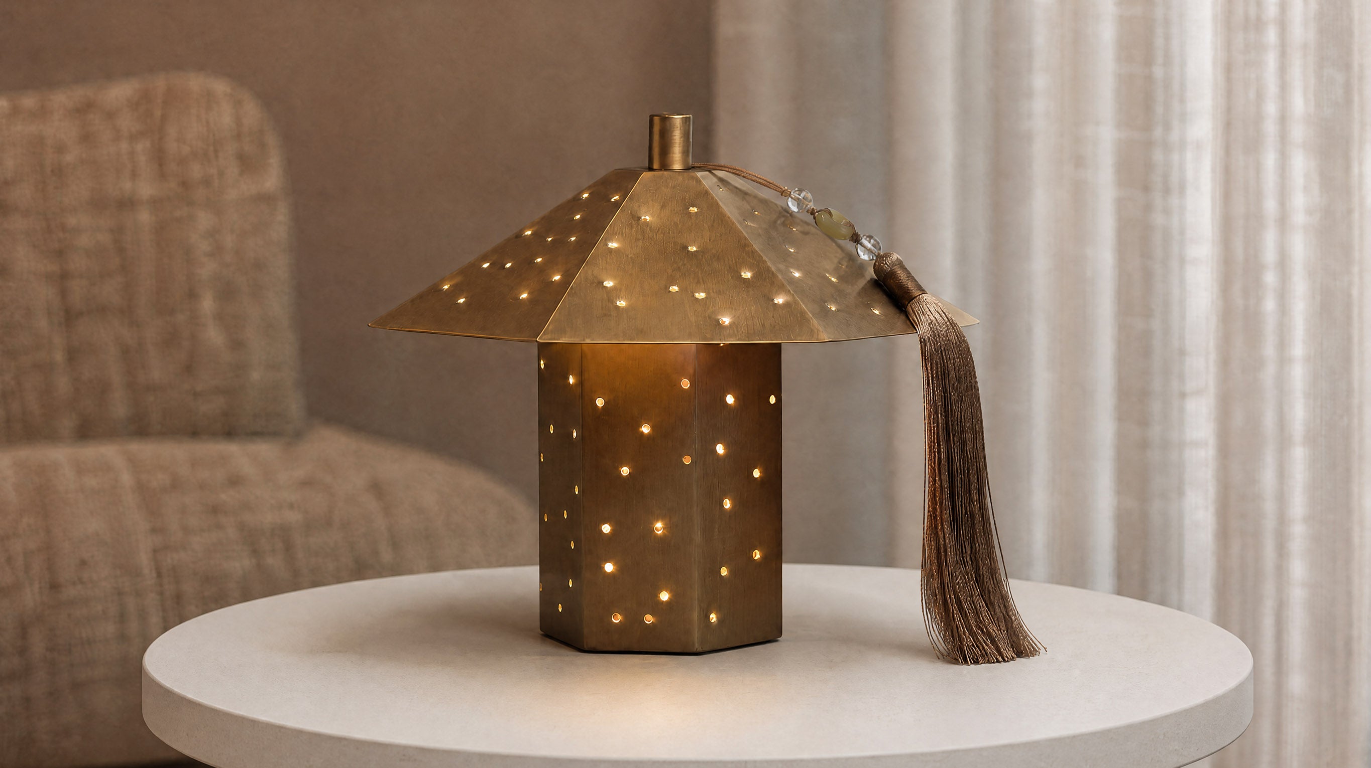 A warm, ambient setting featuring the artamore Polyhedron Starry Night Light in gold, projecting beautiful starry light patterns through its hammered metal surface onto a wabi-sabi textured wall.