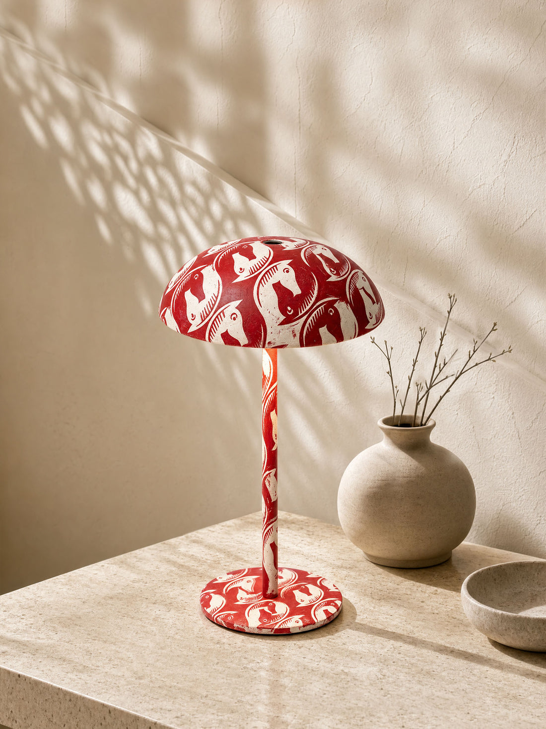 Red patterned mushroom table lamp displayed on a stone console in a warm contemporary interior.