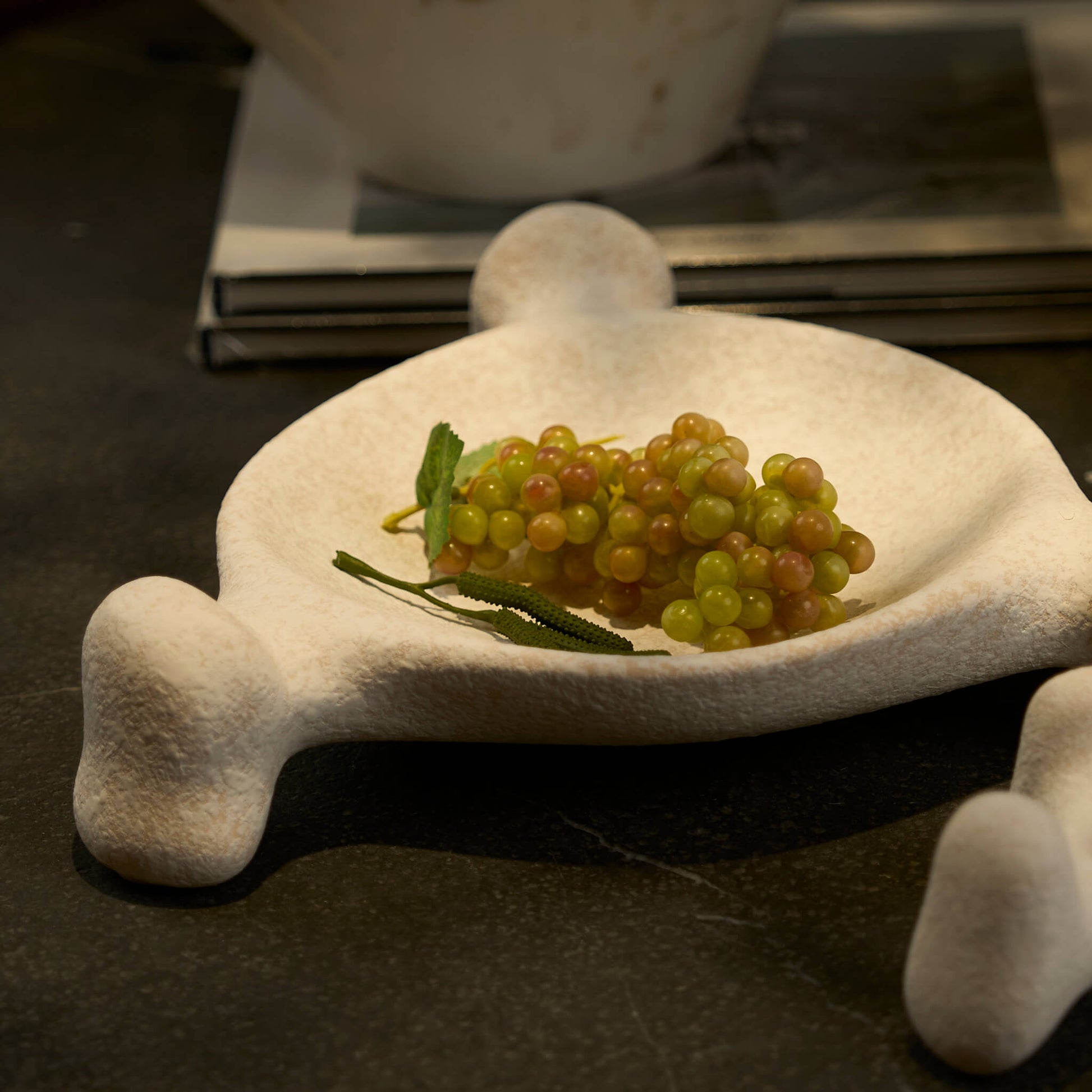 Organic shaped ceramic tray styled elegantly with fruit on a dark stone table