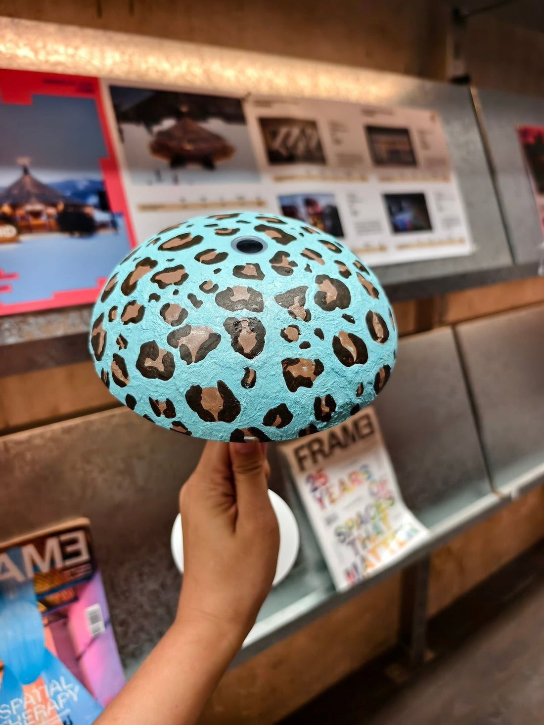 Hand holding a turquoise leopard-print Relax-W DIY portable table lamp customized with a hand-painted design.