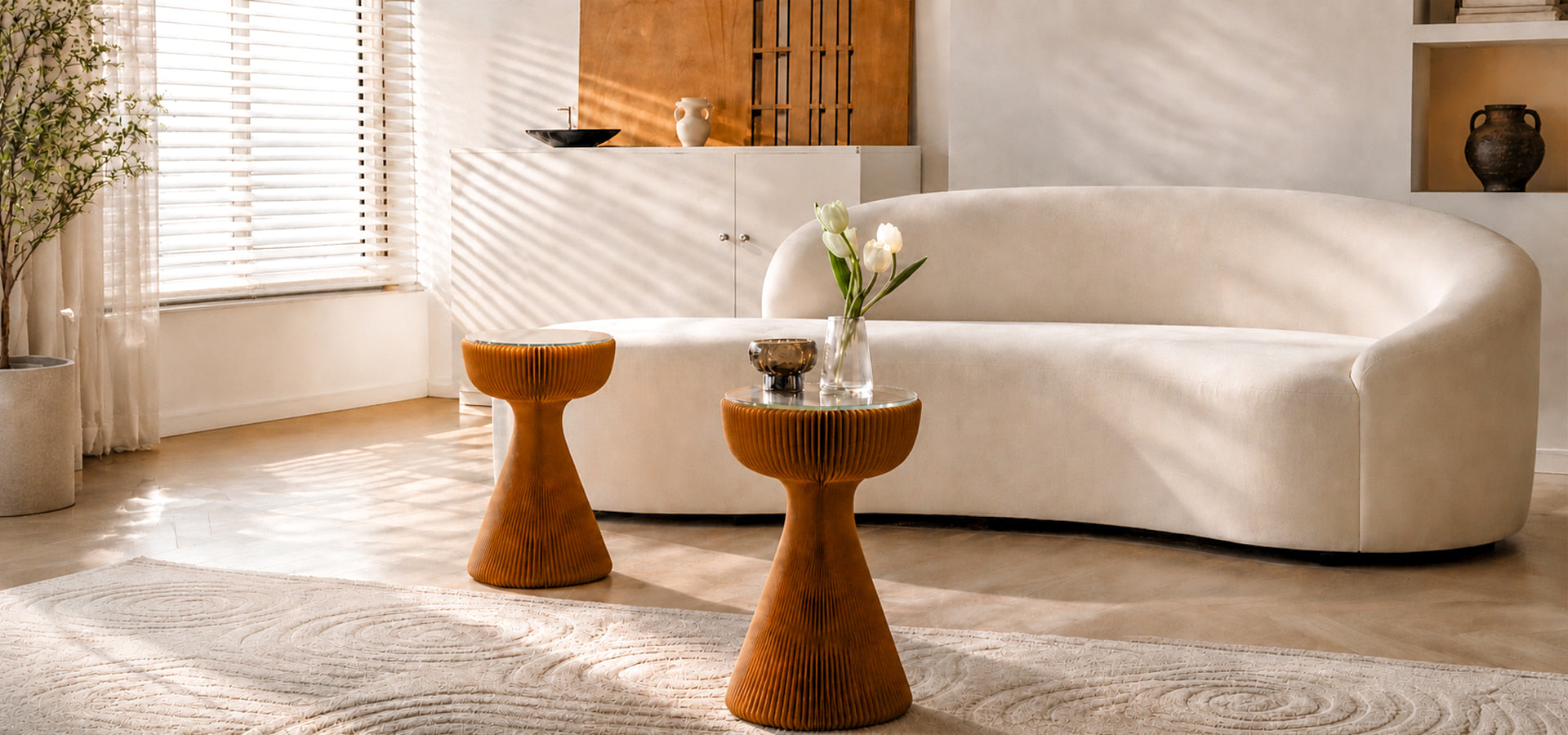 Spaze Paper sculptural honeycomb kraft paper side tables in warm orange beside a curved white sofa in a sunlit modern living room.