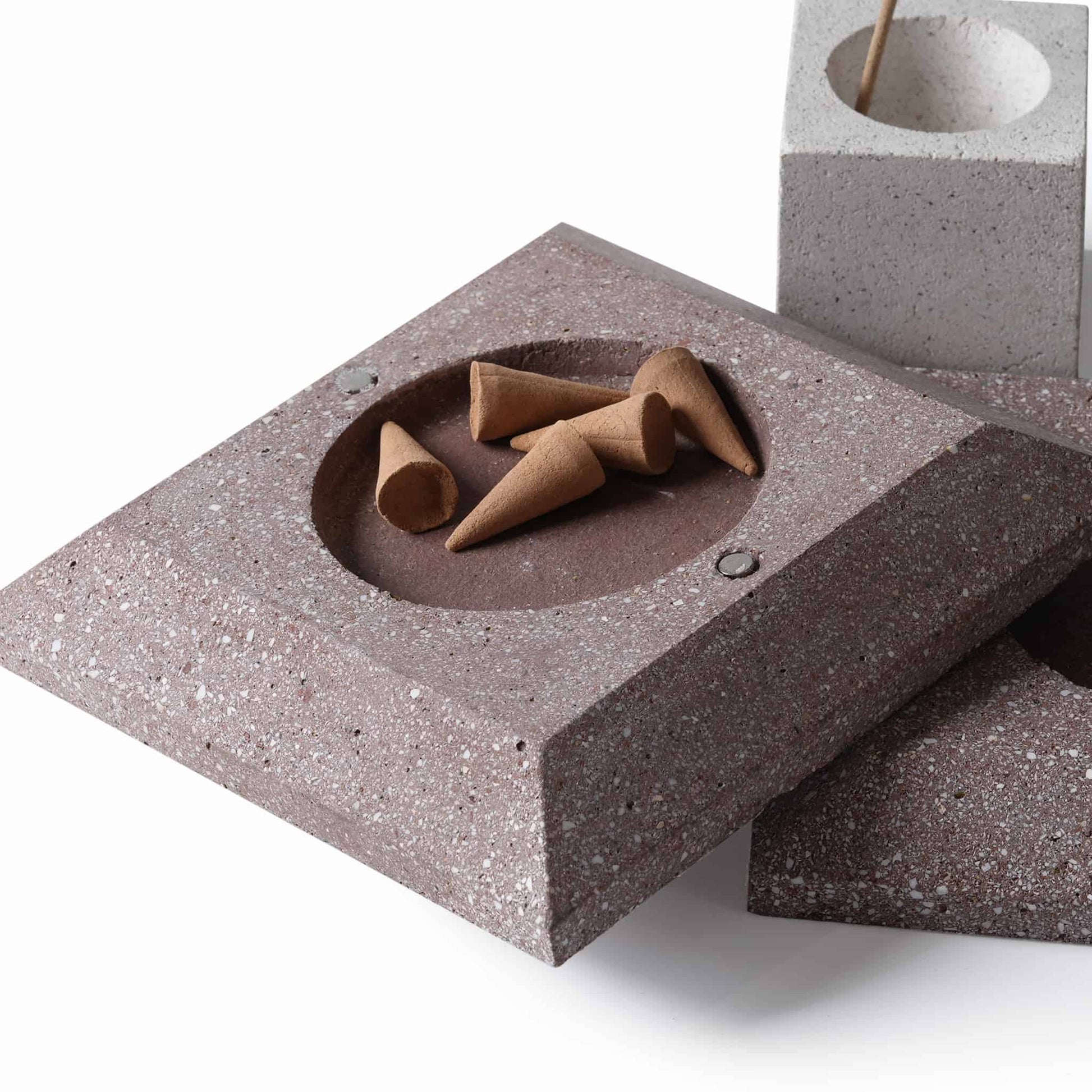 The deep brown square base of the diffuser holding standard cone-shaped tower incense in its circular recess