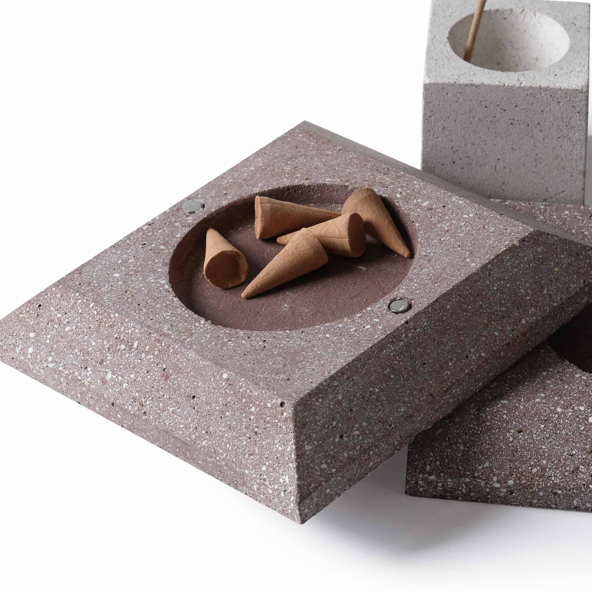 The deep brown square base of the diffuser holding standard cone-shaped tower incense in its circular recess