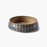 Angled view of the minimalist solid brass Ikebana bowl with a silver-toned square-grid exterior.
