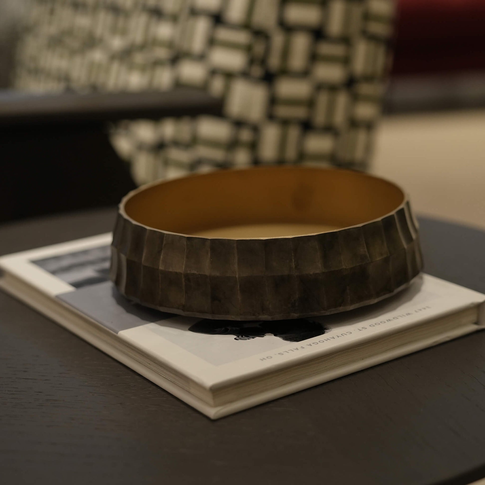 The minimalist brass decorative bowl styled on a coffee table book in a modern European living room