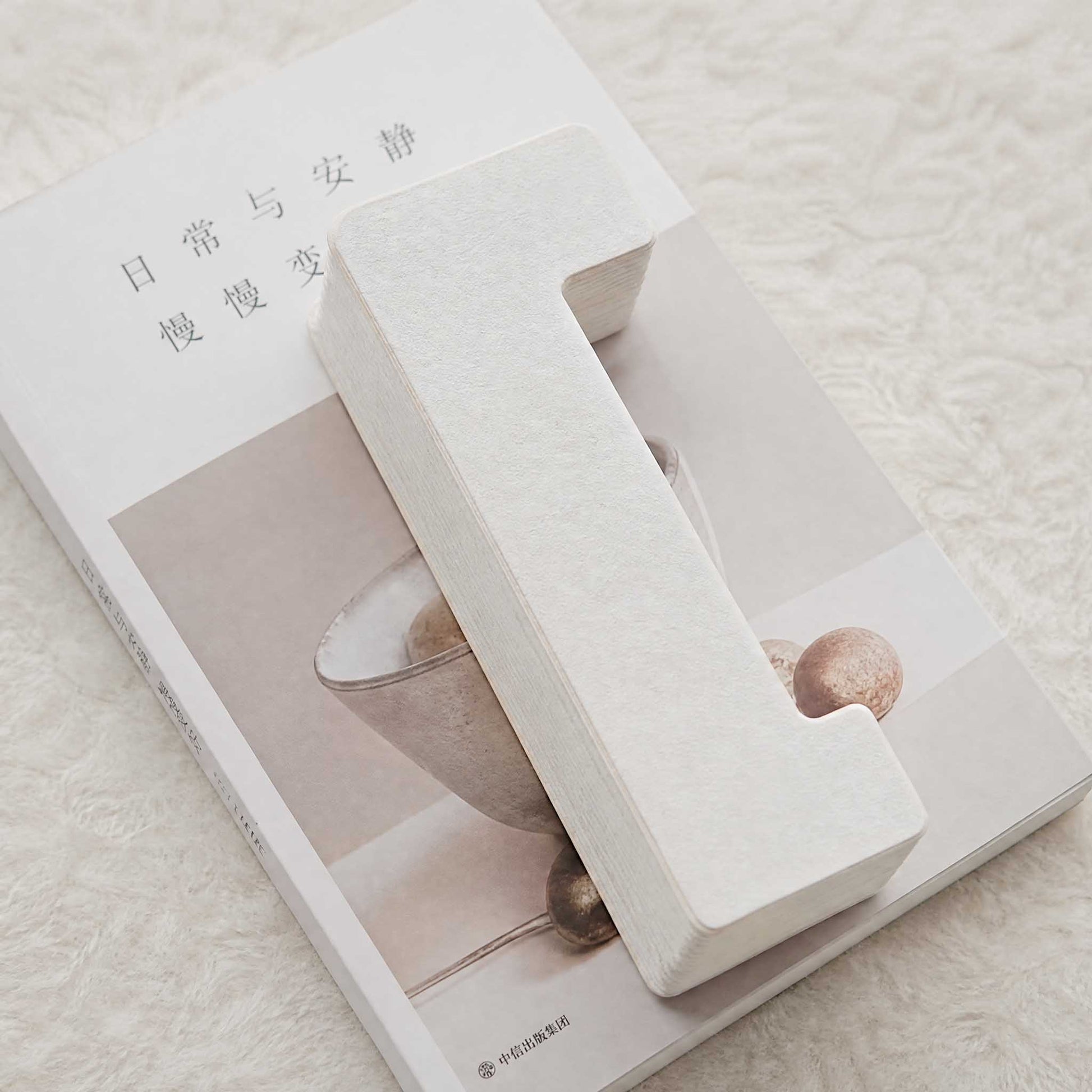Folded Bamboo Zen paper lampshade on a book, showing its compact flat storage design.