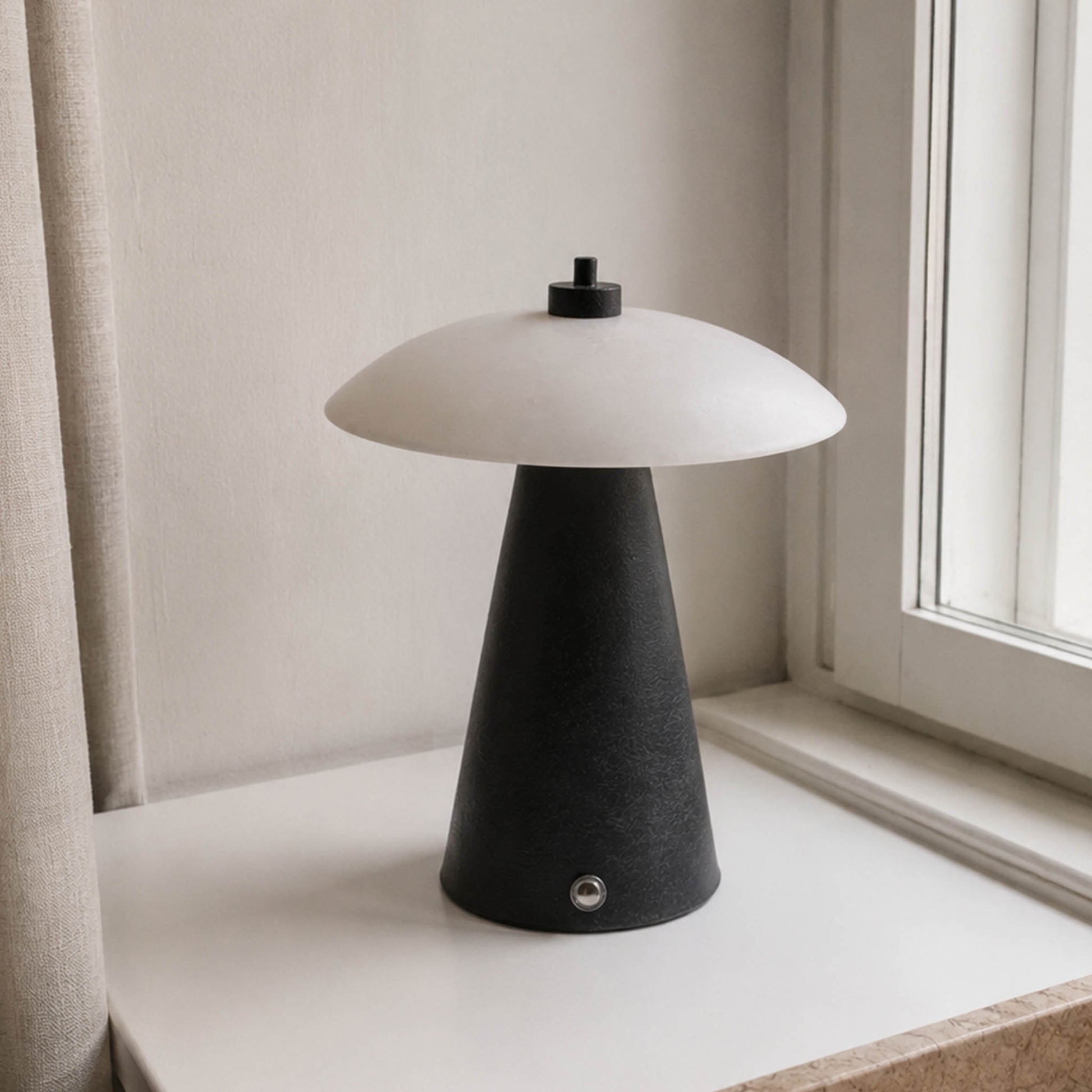 Minimal black marble night light with a white natural stone shade on a bright window sill.