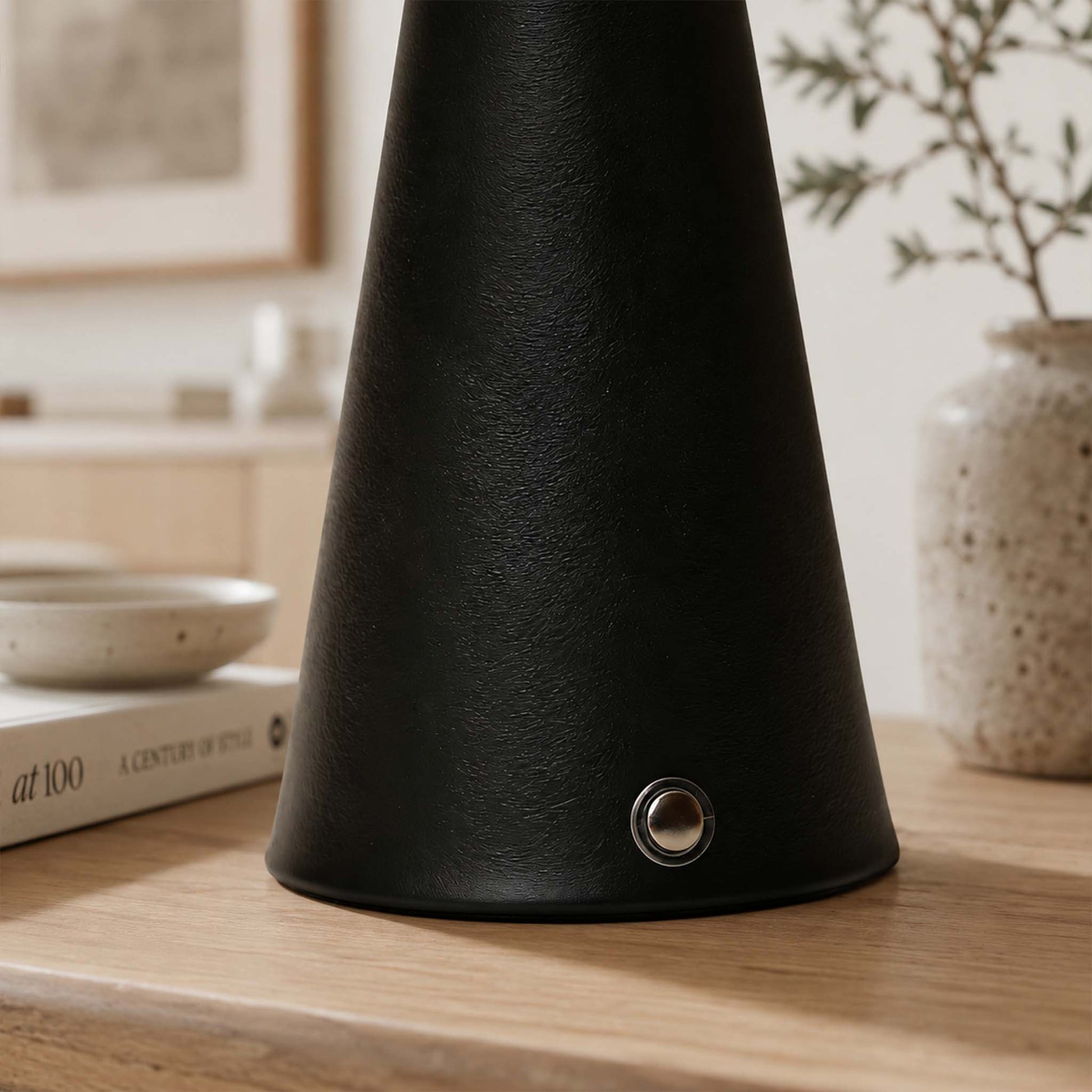 Close-up of the black textured metal lamp body with a small round control button.